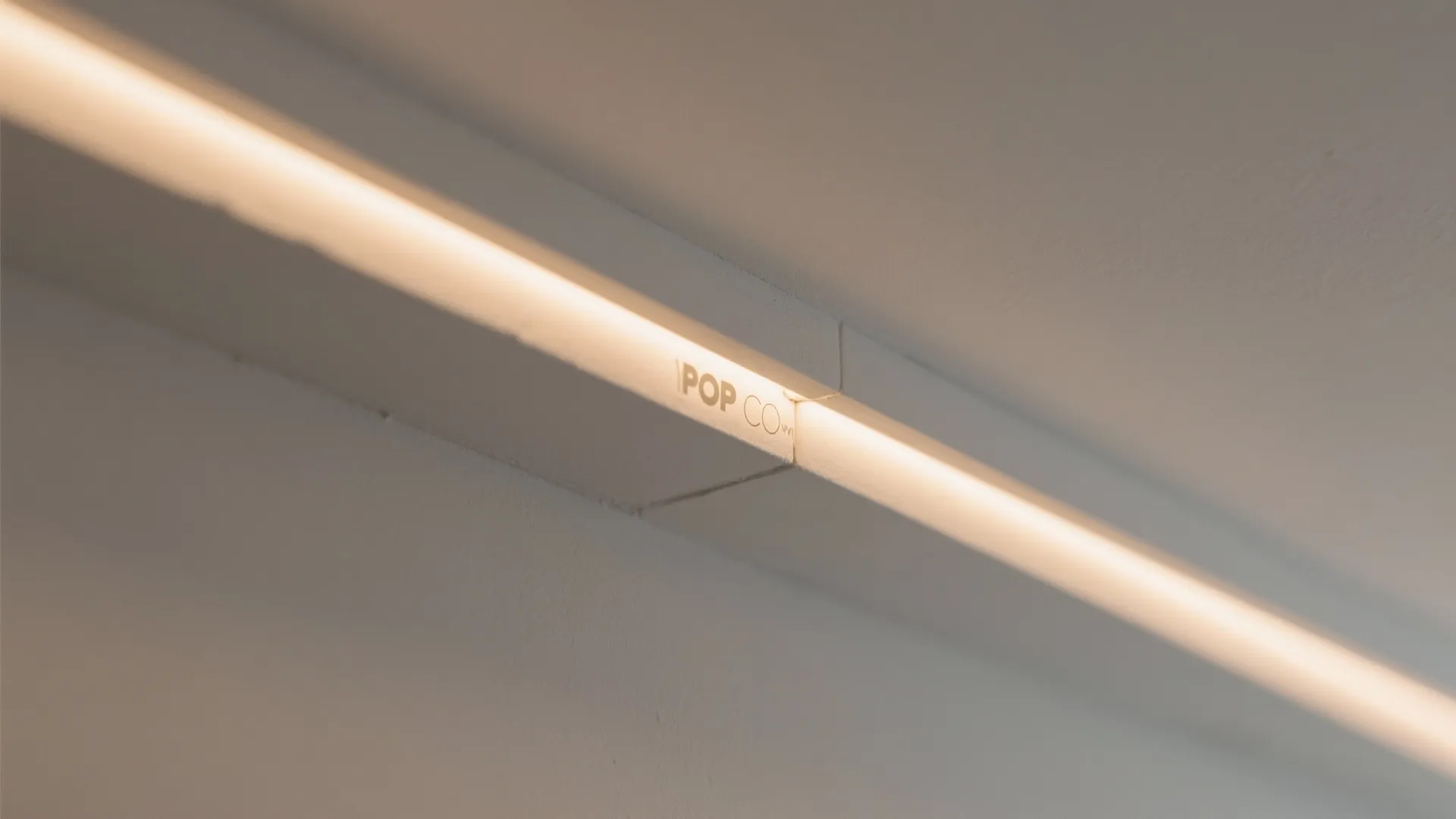Close up view of a modern recessed warm light strip installed into a white ceiling