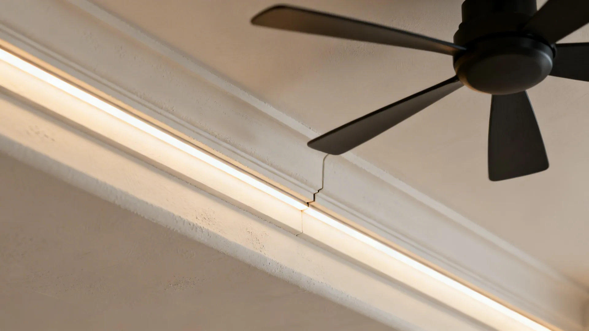 Macro of a gypsum fan island edge and linear cove with diffused warm LED showing precise miter work.