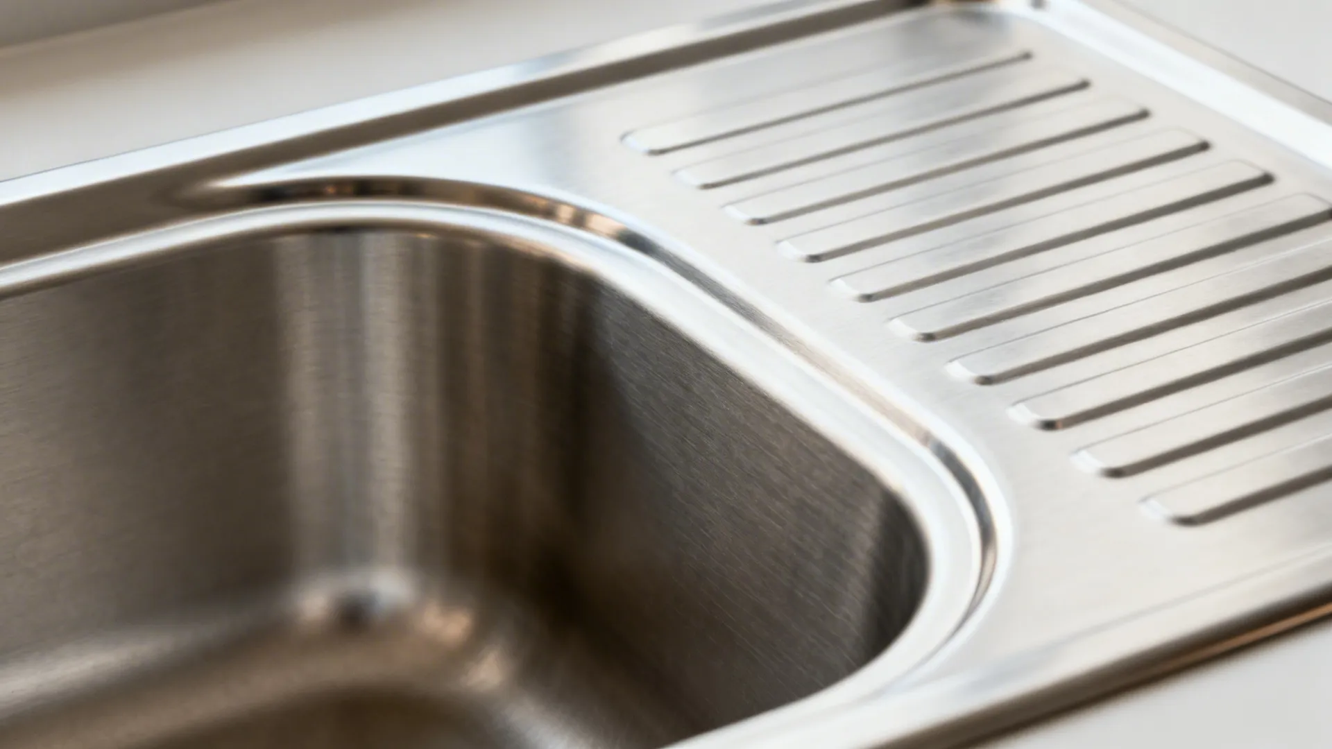 Macro of integrated stainless sink and coved backsplash radius with brushed texture.