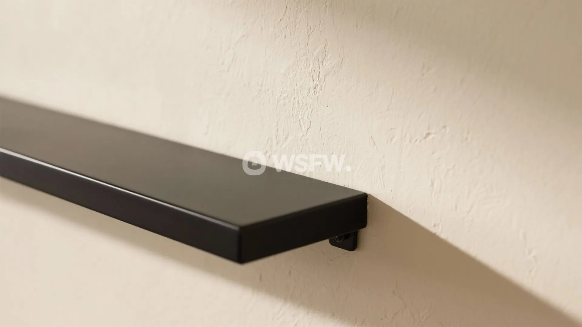 Close up of black wall shelf mounted on textured cream wall with clean simple lines