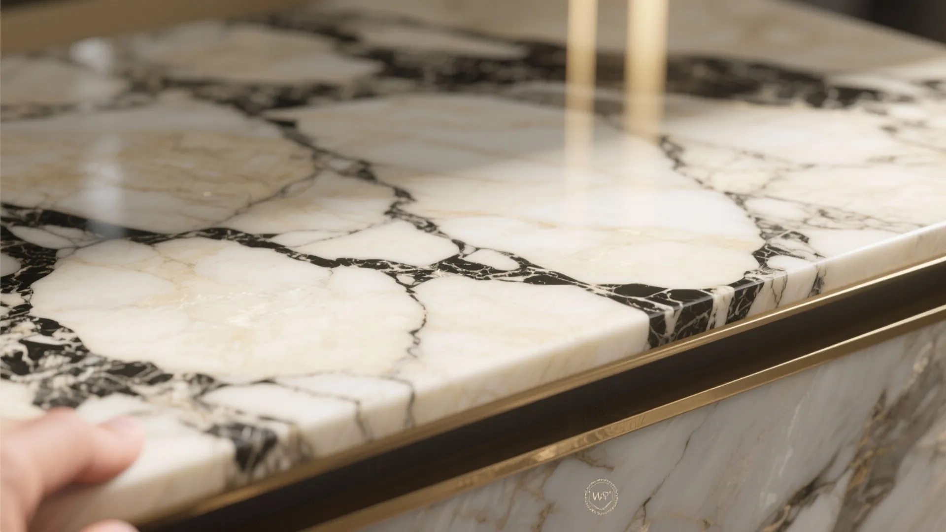 Close up of cream marble stone countertop with black veins and gold metal edge detail