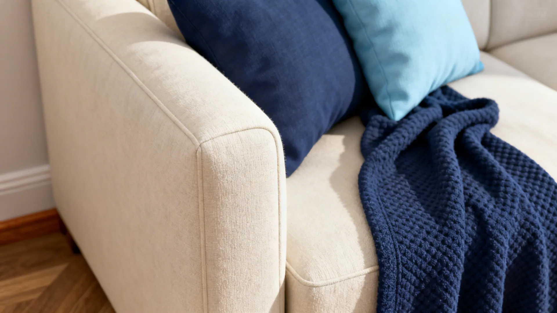 Close-up of cream sofa with navy and powder-blue pillows and washable throw