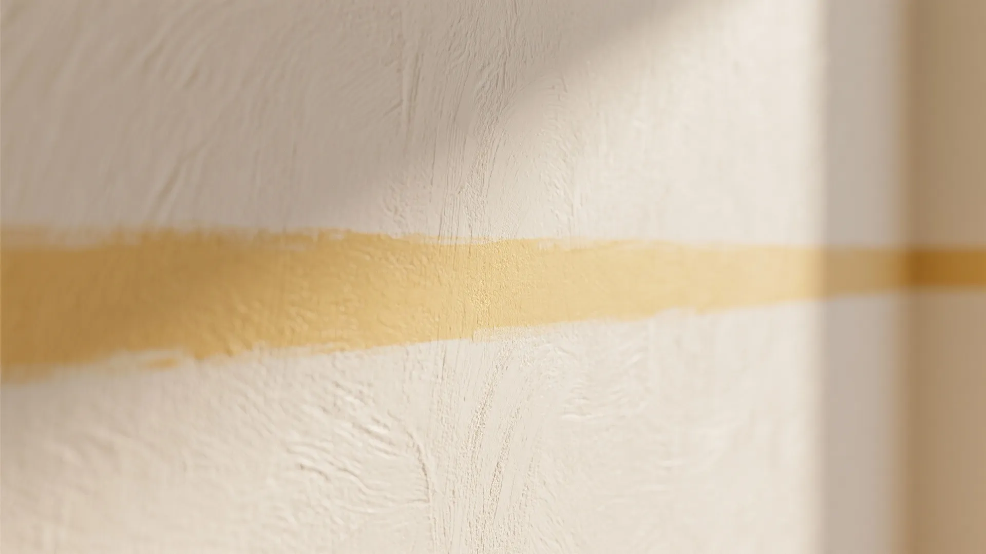 Close up of textured white wall with horizontal yellow paint stripe and soft indoor lighting