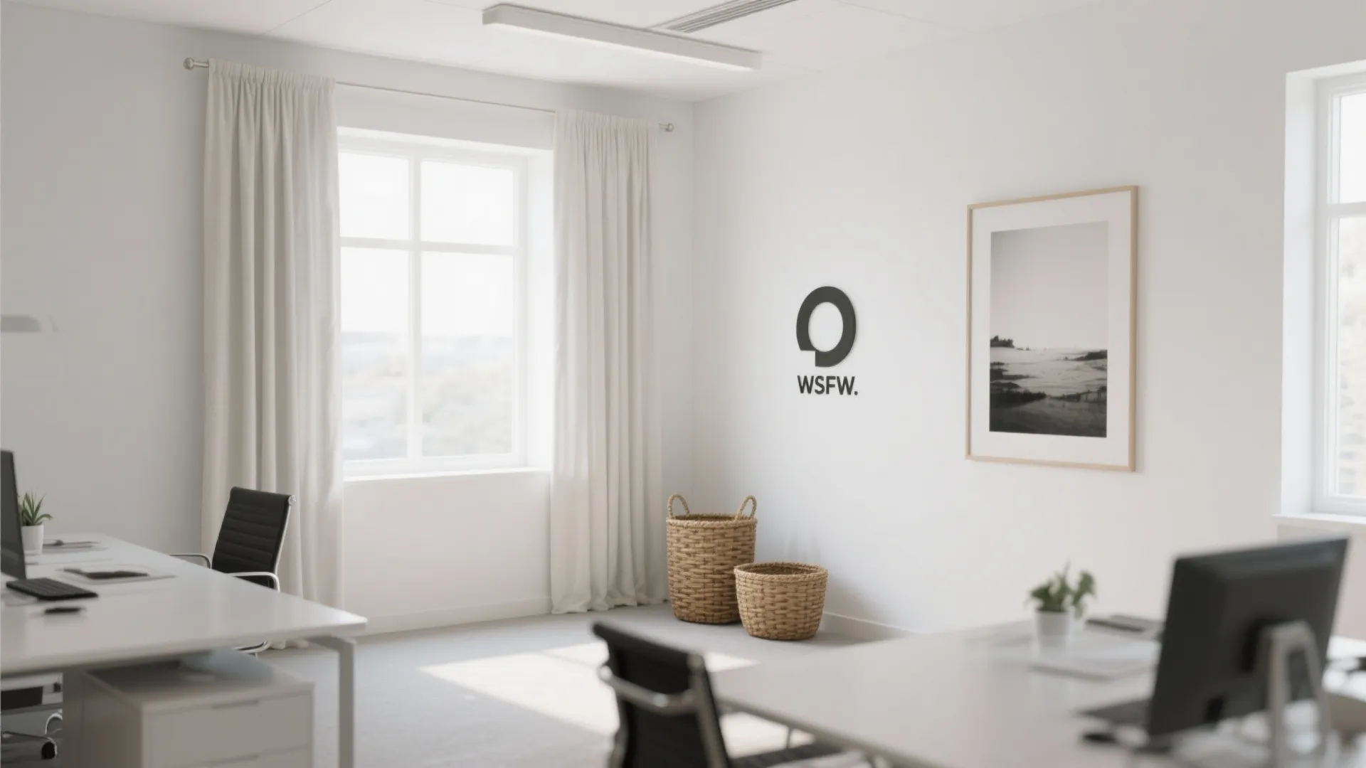 Minimalist white office with desks and black chairs plus white curtains and two woven baskets