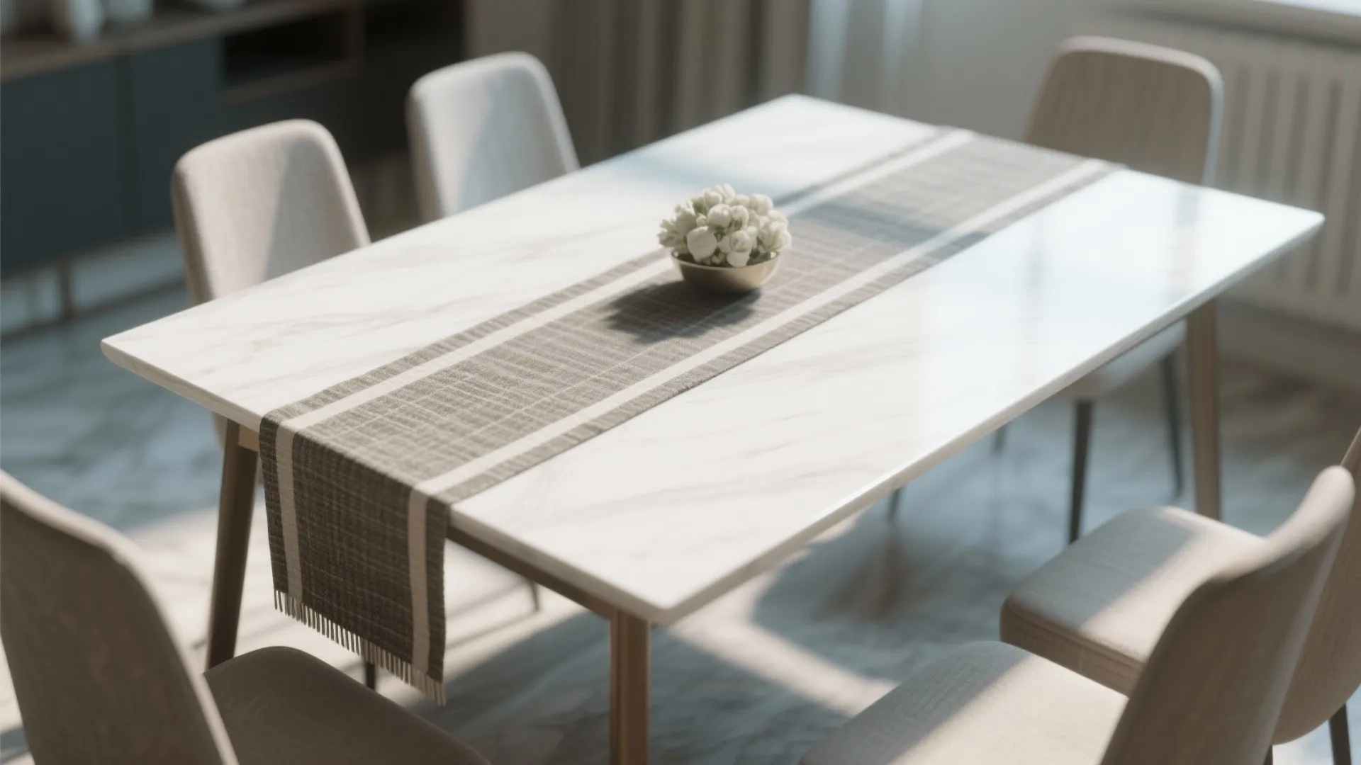 Modern marble dining table with grey cloth runner white flowers and neutral color dining chairs