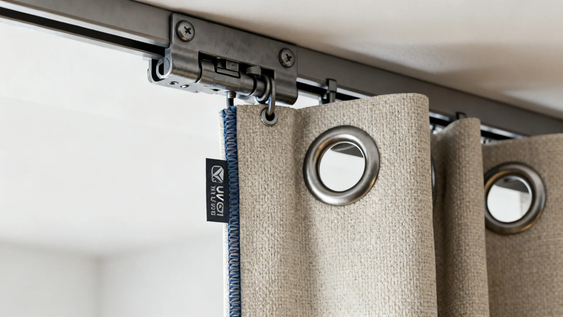 Close up of metal curtain rings and track hardware on beige textured fabric window curtains