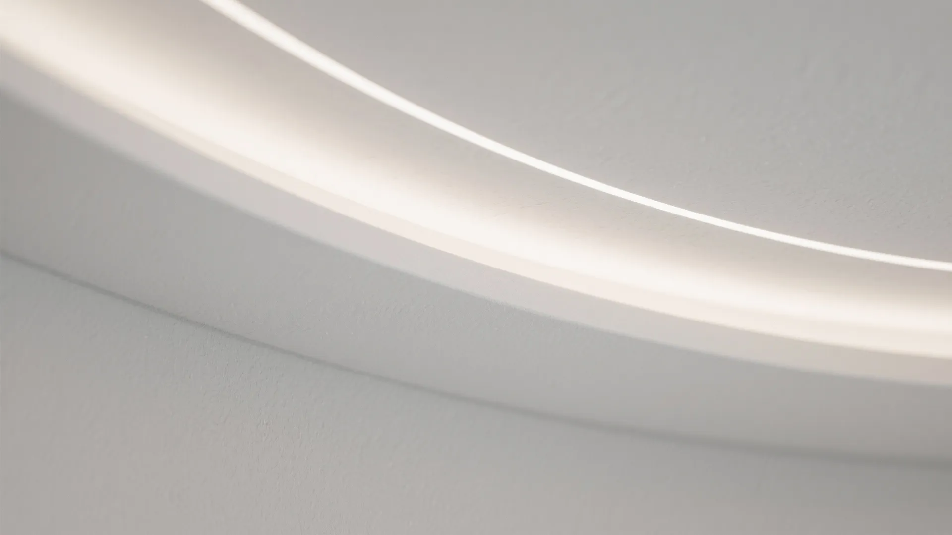 Close up of a curved white ceiling with bright hidden light strip and soft grey shadows