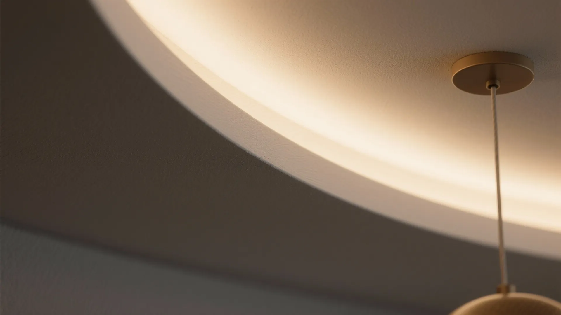 Close up view of curved ceiling edge with warm hidden light and a hanging fixture