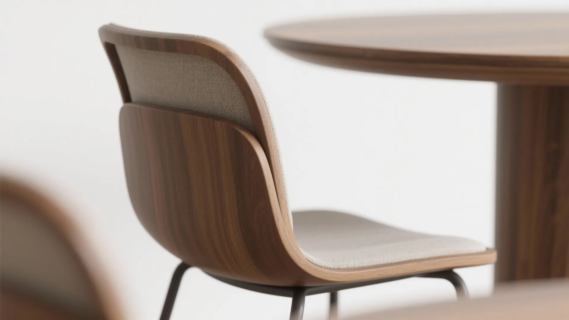 Close up of a wooden chair with a curved backrest and light grey fabric cushion