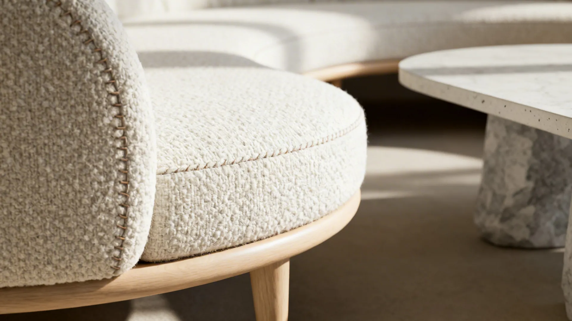 Macro of a curved-edge diwan in tight-loop boucle with refined stitching and soft light.