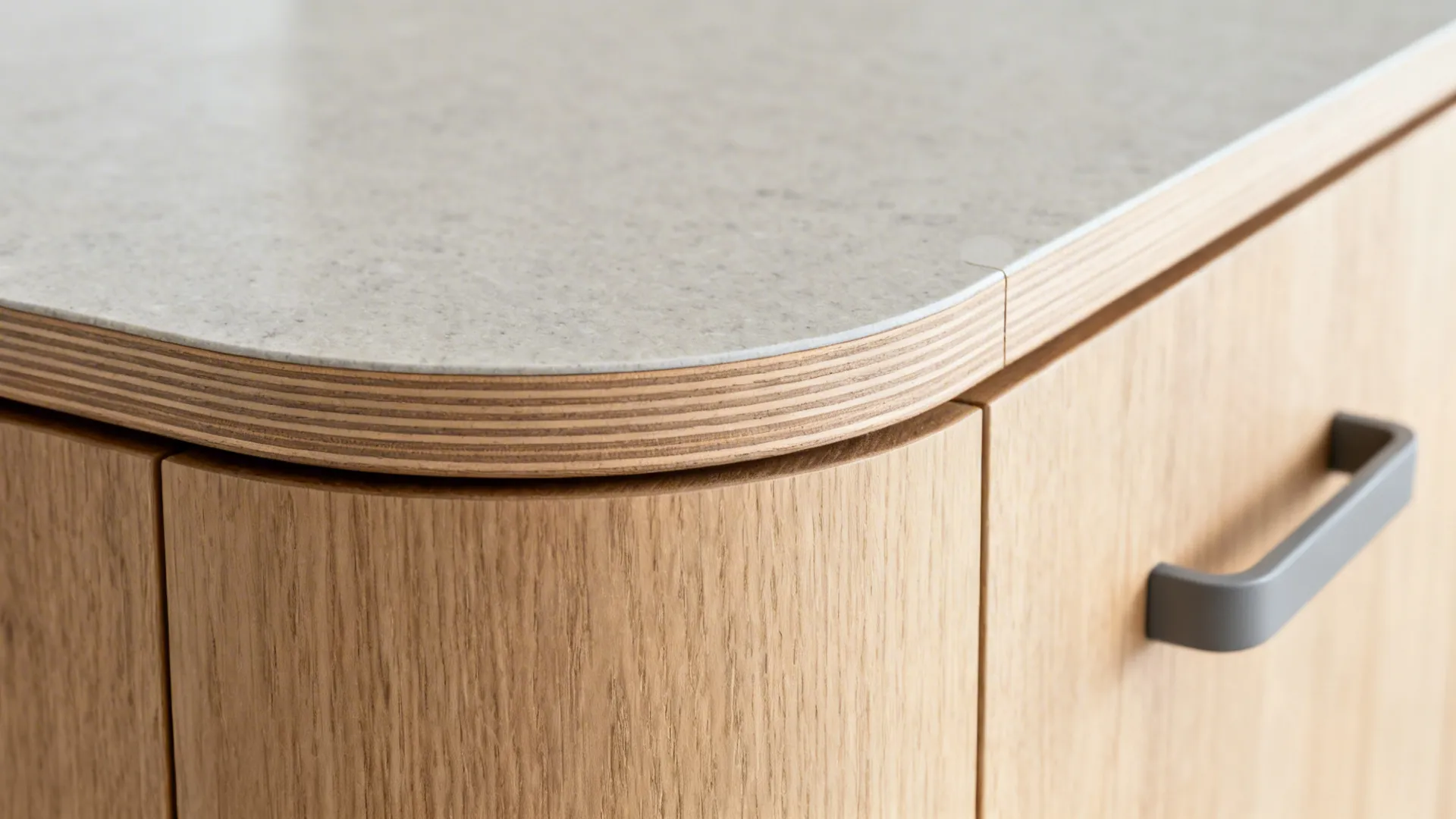Close-up of a rounded wood island corner meeting a matte quartz countertop.