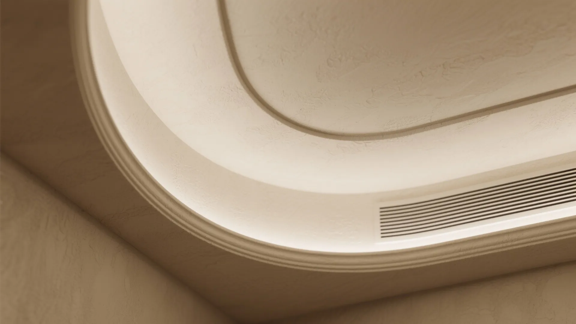 Close up view of a curved cream ceiling with hidden light and a small vent