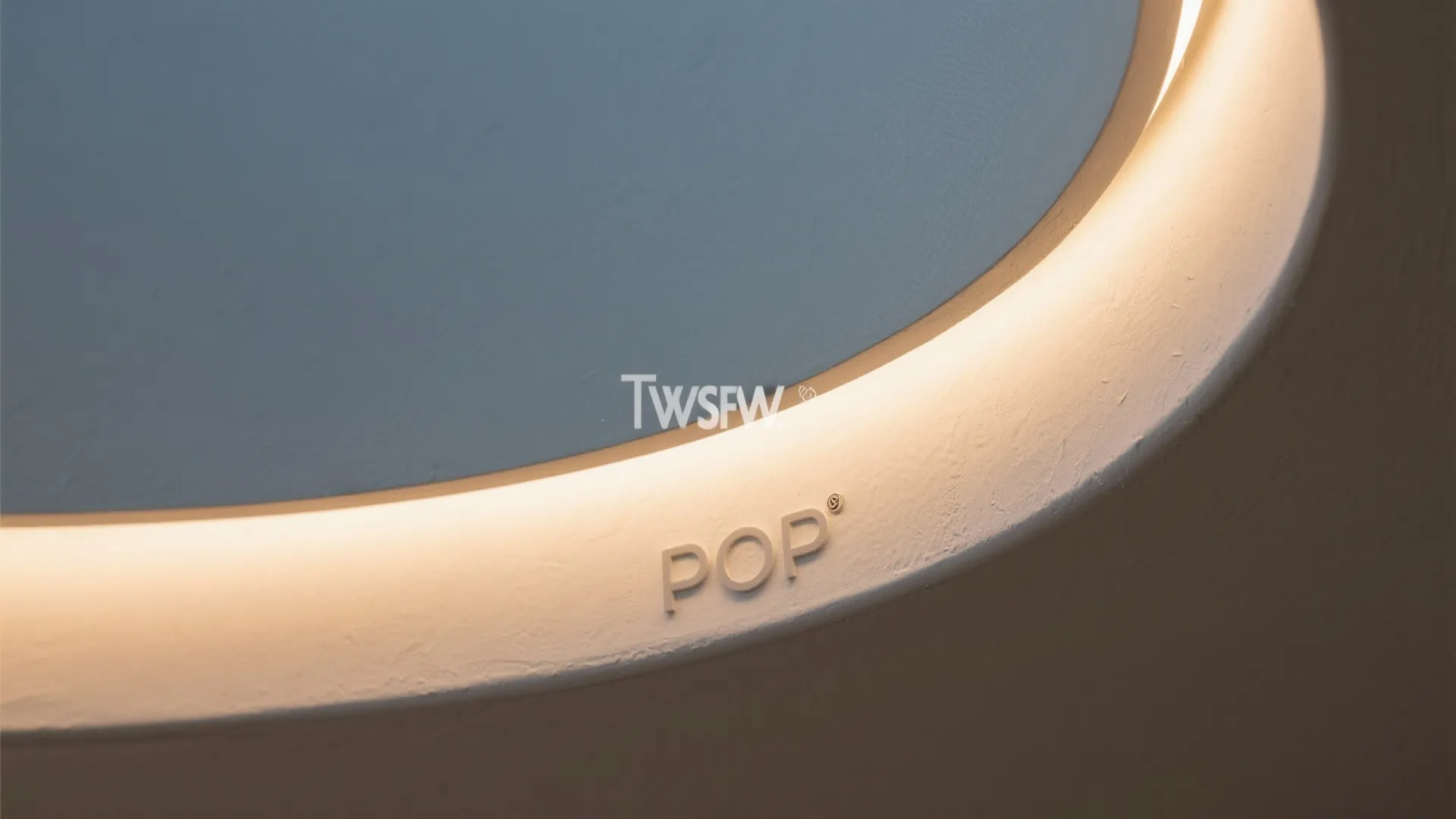 Close up of curved wall panel with warm hidden light strip and pop logo detail