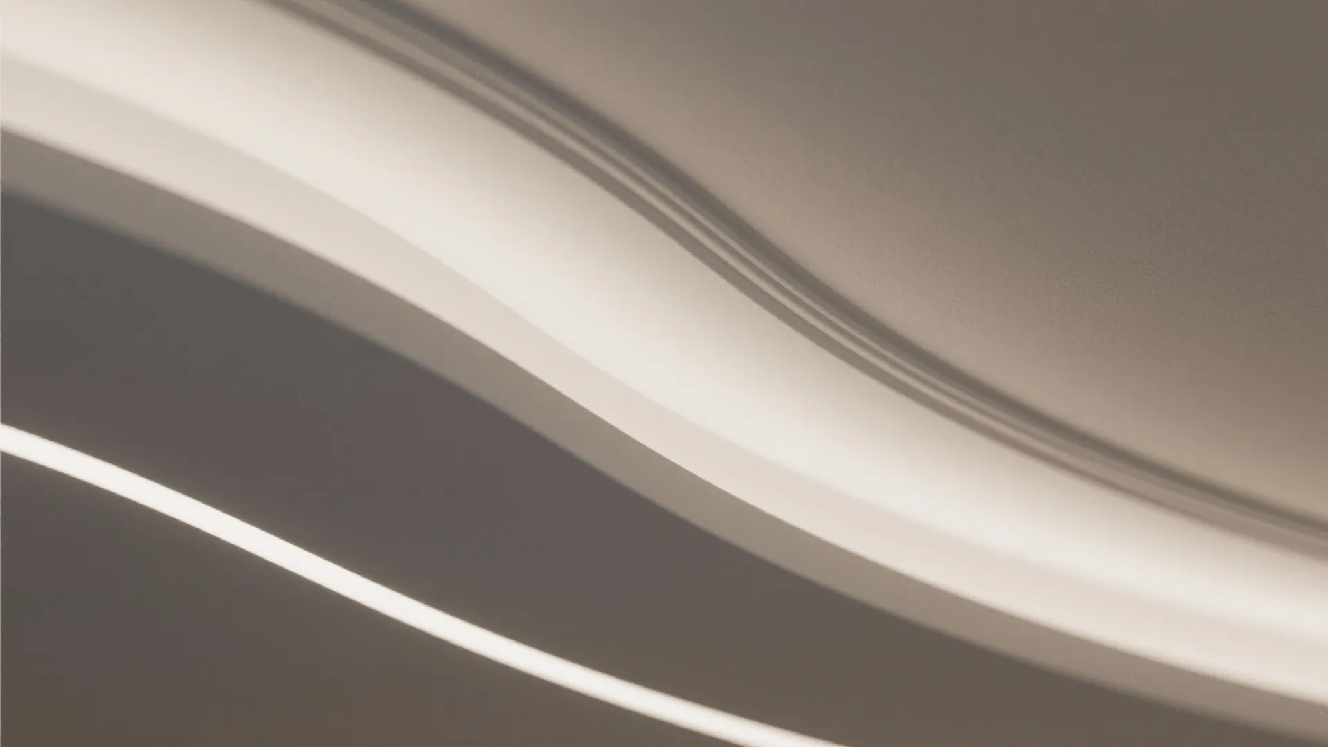 Macro of a smooth curved gypsum ceiling edge with a clean LED diffuser and matte finish.
