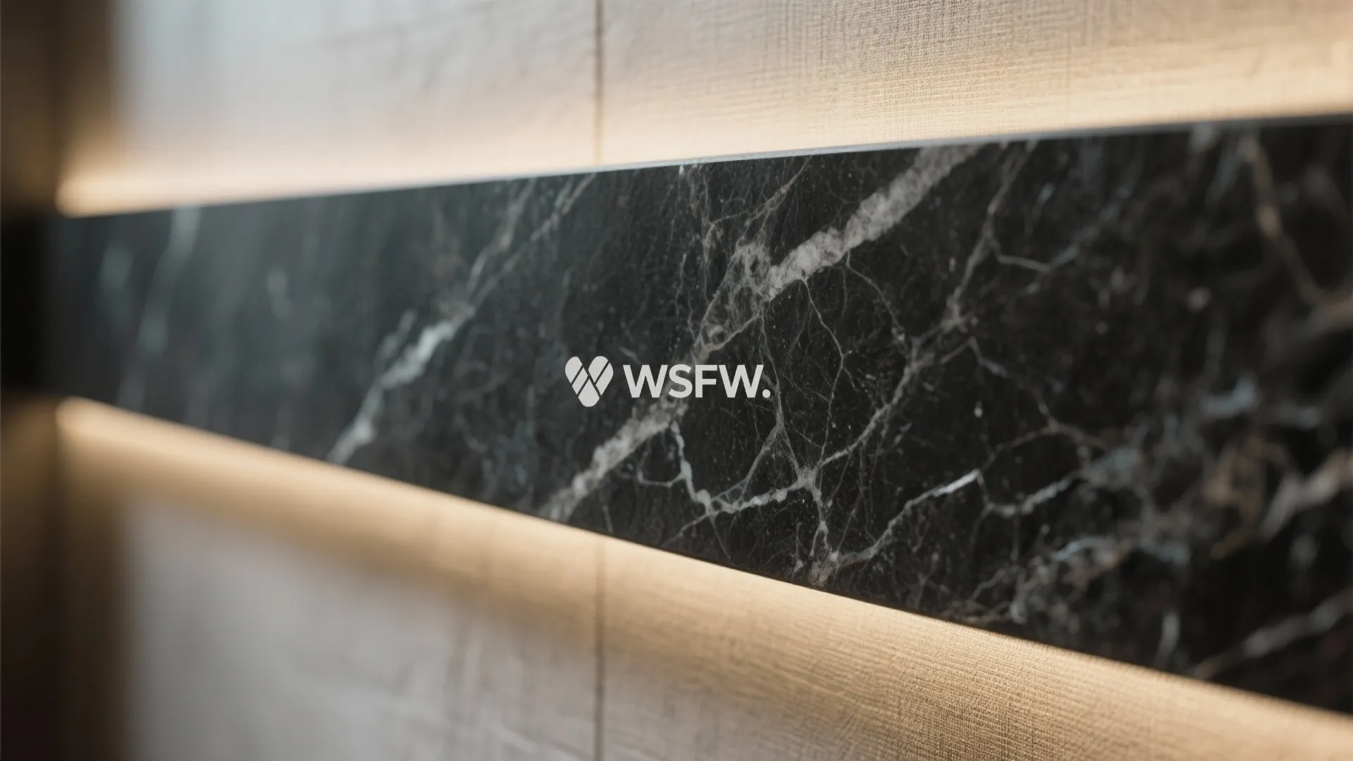 Close up of black marble wall panel with white veins and soft yellow led lighting strips