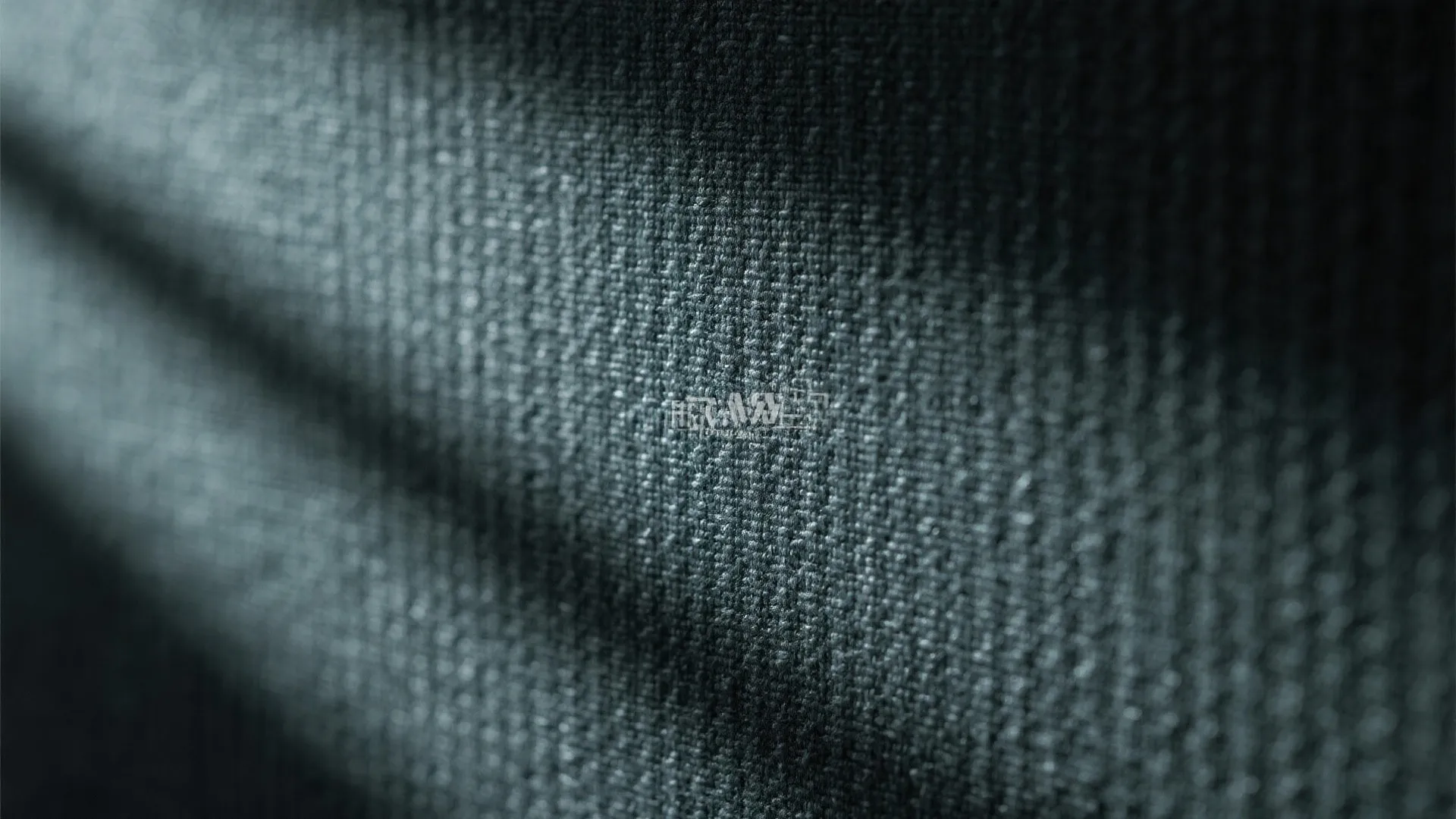 Close up view of dark grey fabric texture showing detailed woven patterns with soft lighting