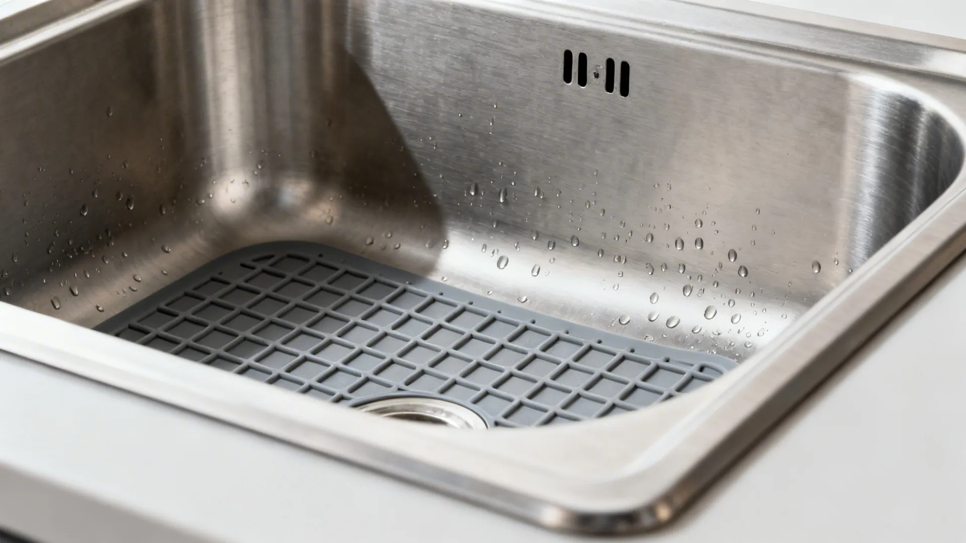 Macro look at a deep single-bowl sink with a silicone grid protecting the brushed steel base.