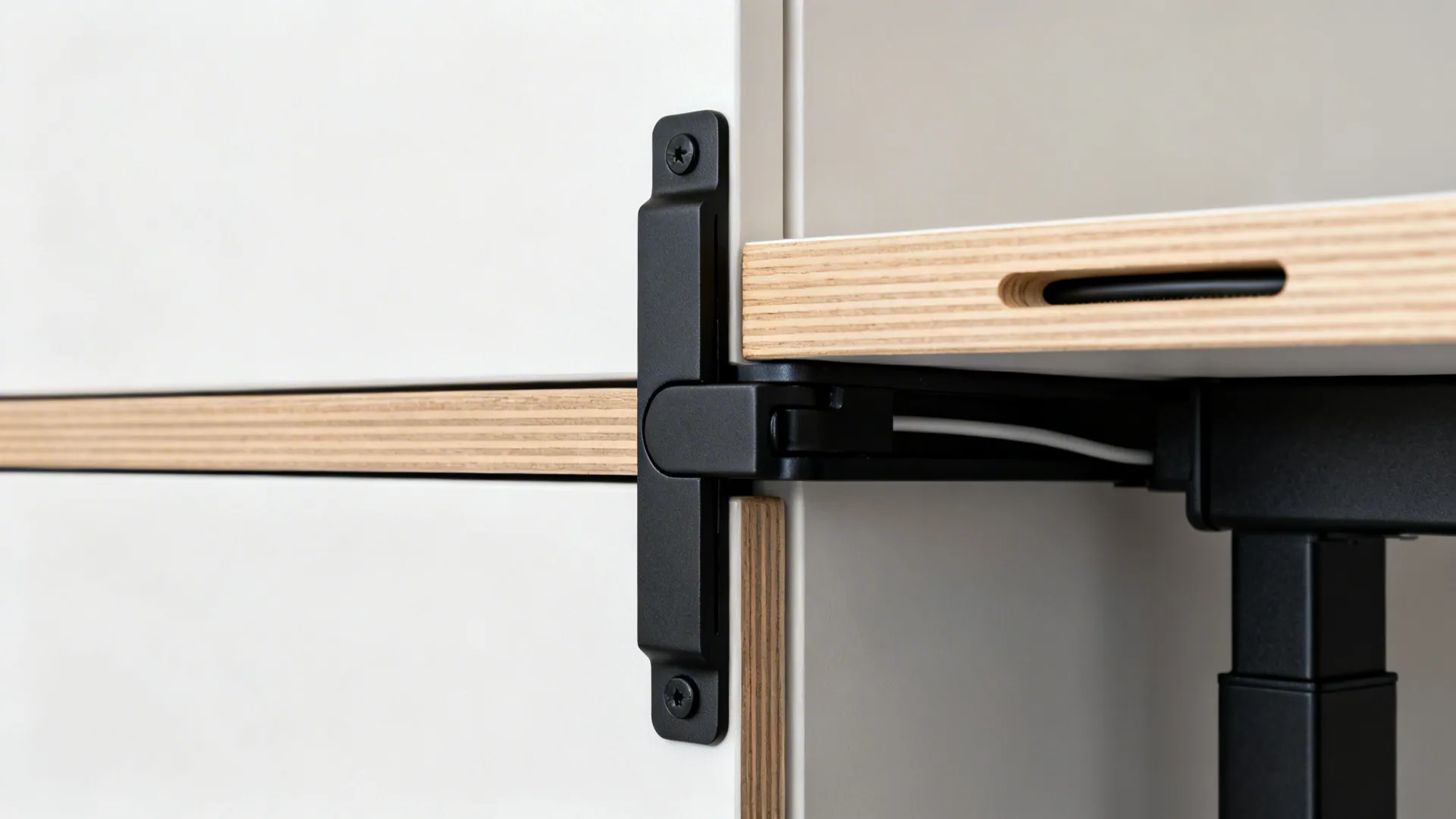 Macro of fold-down desk hinge and hidden support arm with oak edging and recessed cable channel.