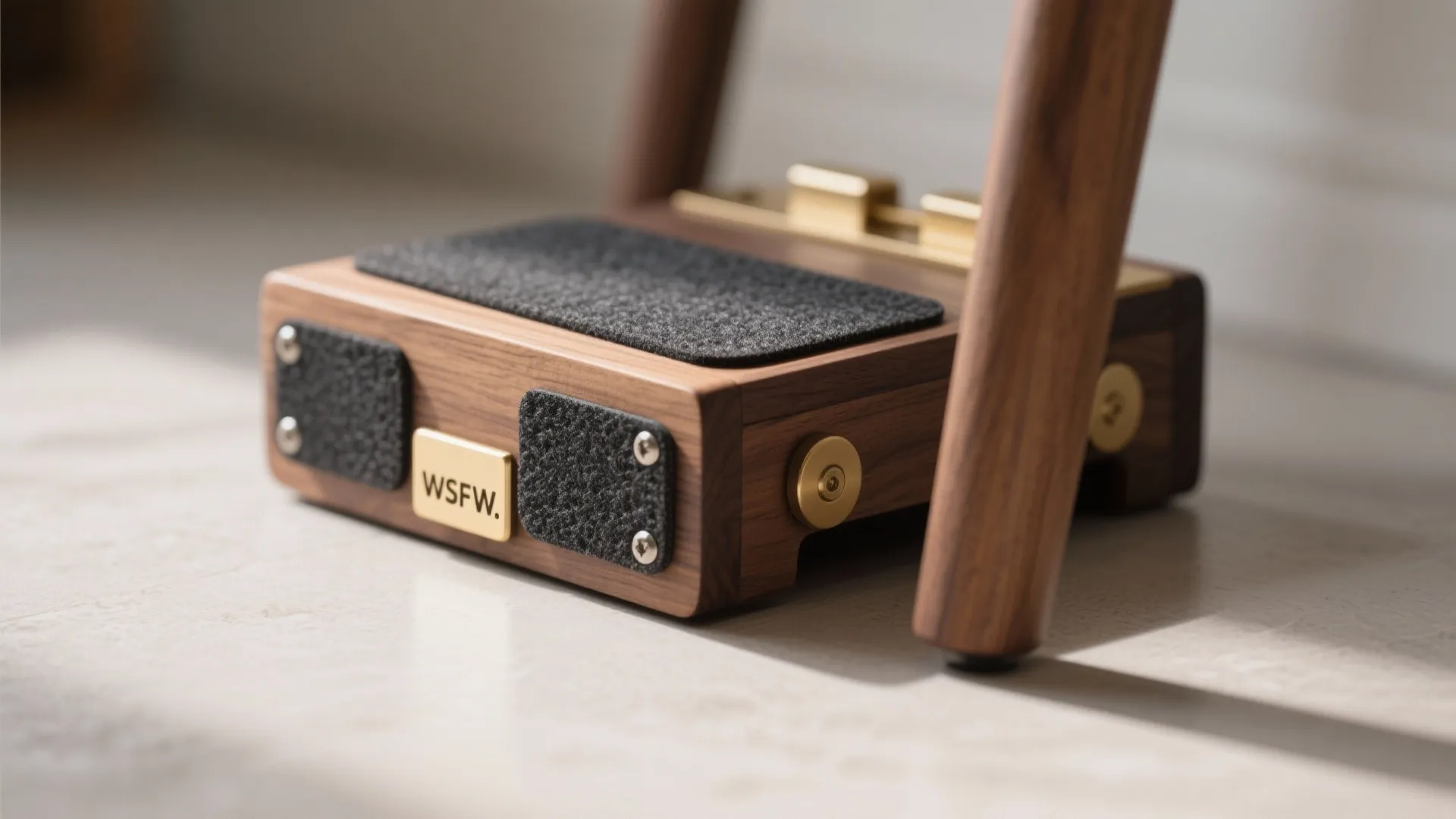 Close up of wooden furniture base with black grip pads and gold metal parts on surface