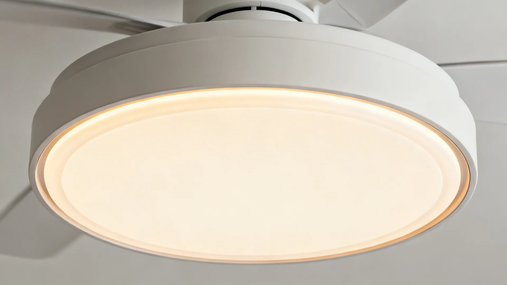 Close-up of a ceiling disc edge with a recessed fan hub and soft ring diffuser glow.