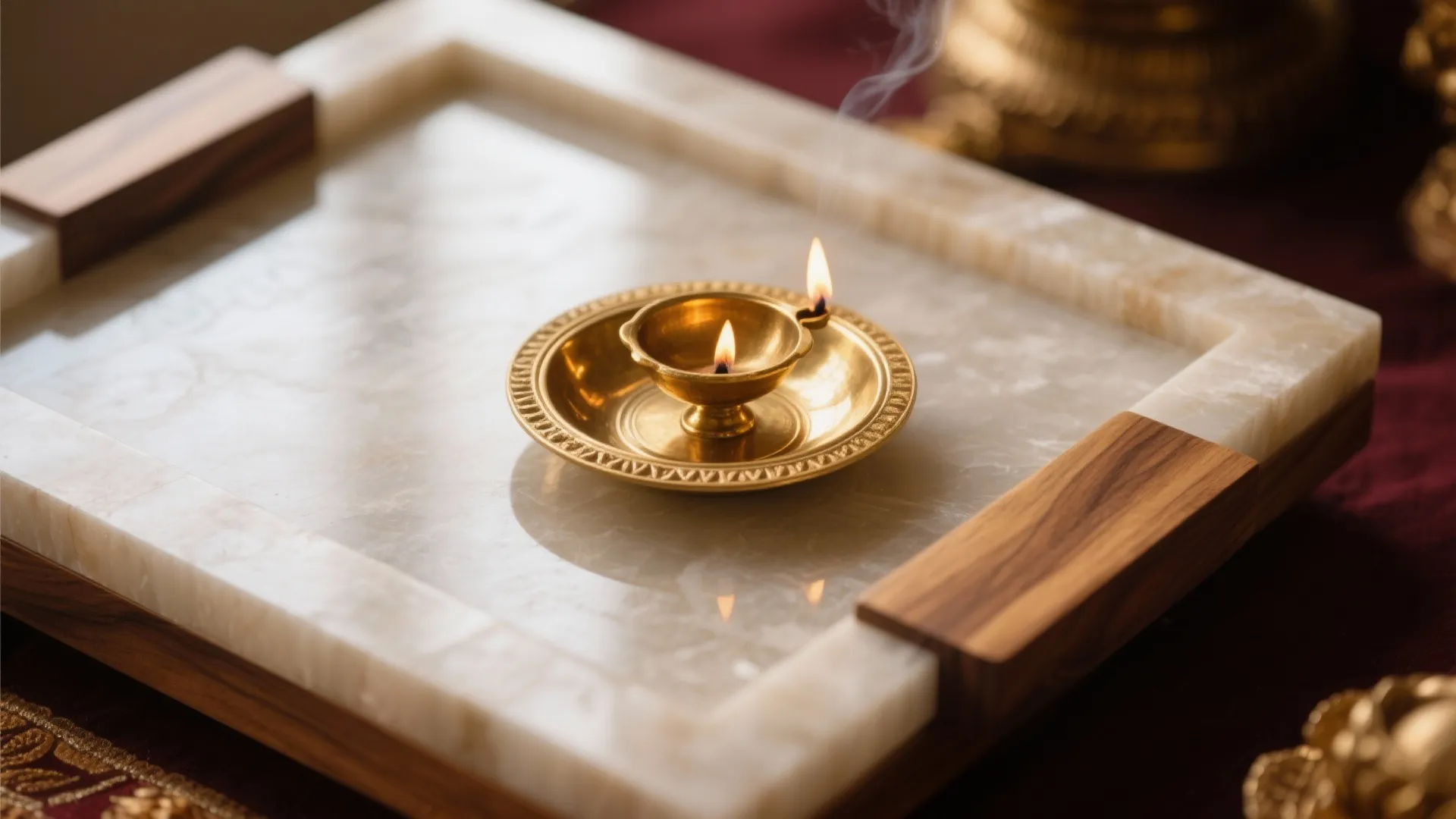 Small brass oil lamp with burning flame sitting on white marble tray with wooden handles detail
