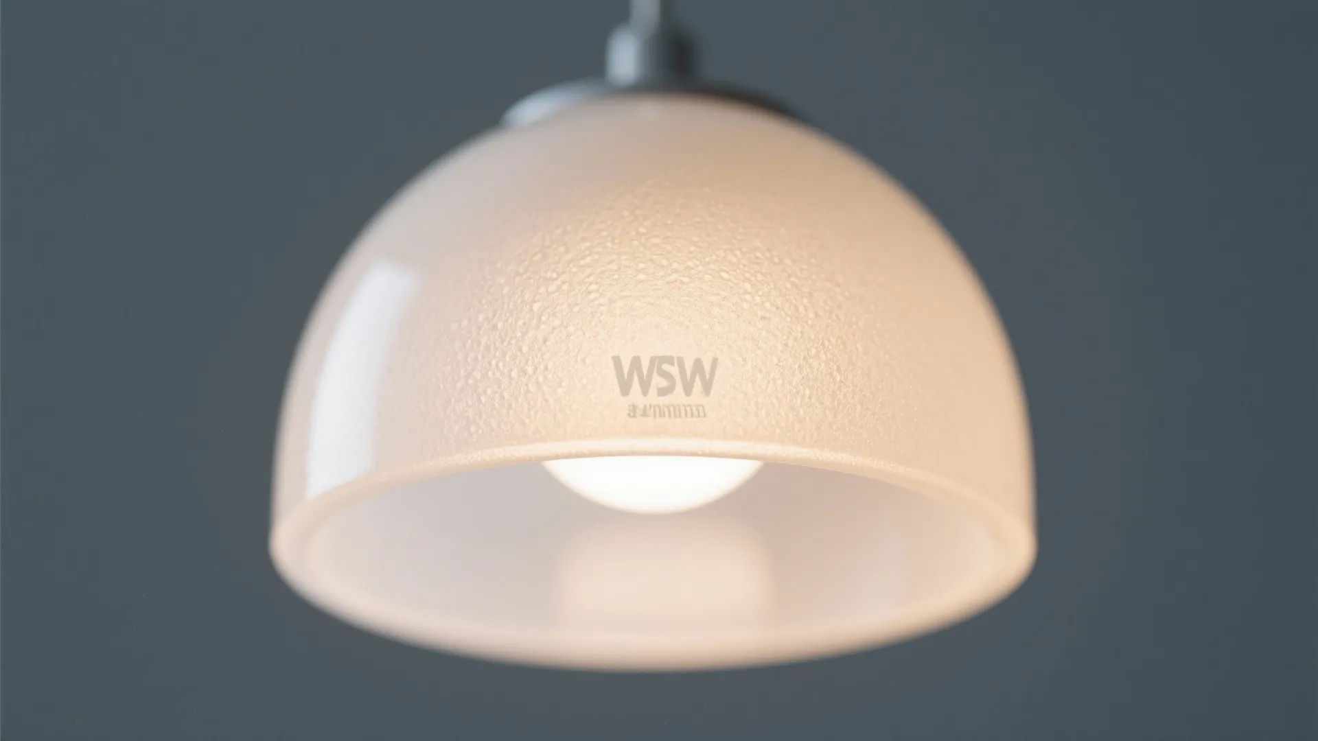 White dome ceiling light cover with textured surface and a glowing bulb on dark background