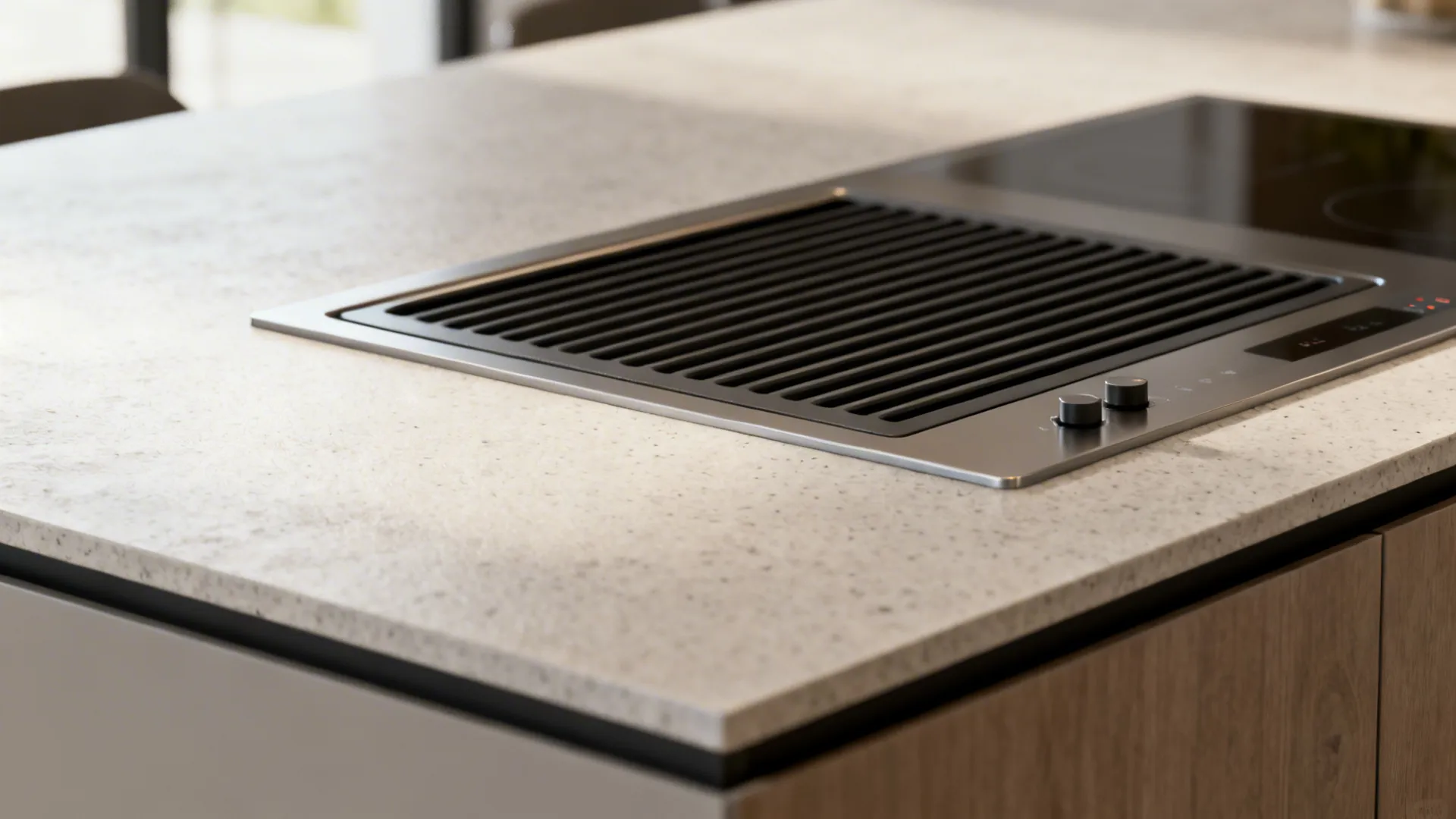 Close up of black ventilation fan built into stone countertop next to modern glass stove top
