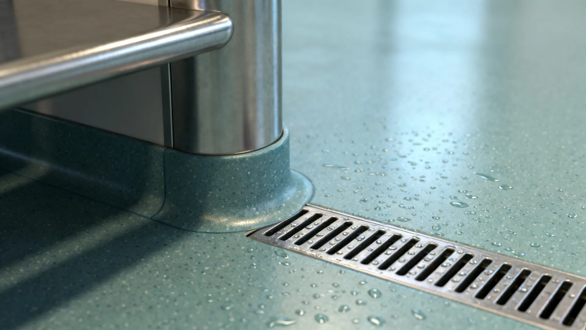 Macro of coved epoxy floor meeting stainless leg and linear drain.