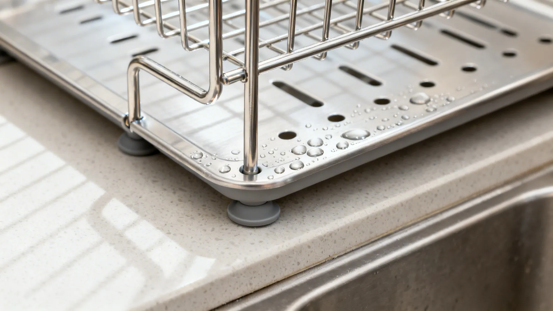 Macro of an over-sink rack’s removable drip tray with water beads and silicone foot.
