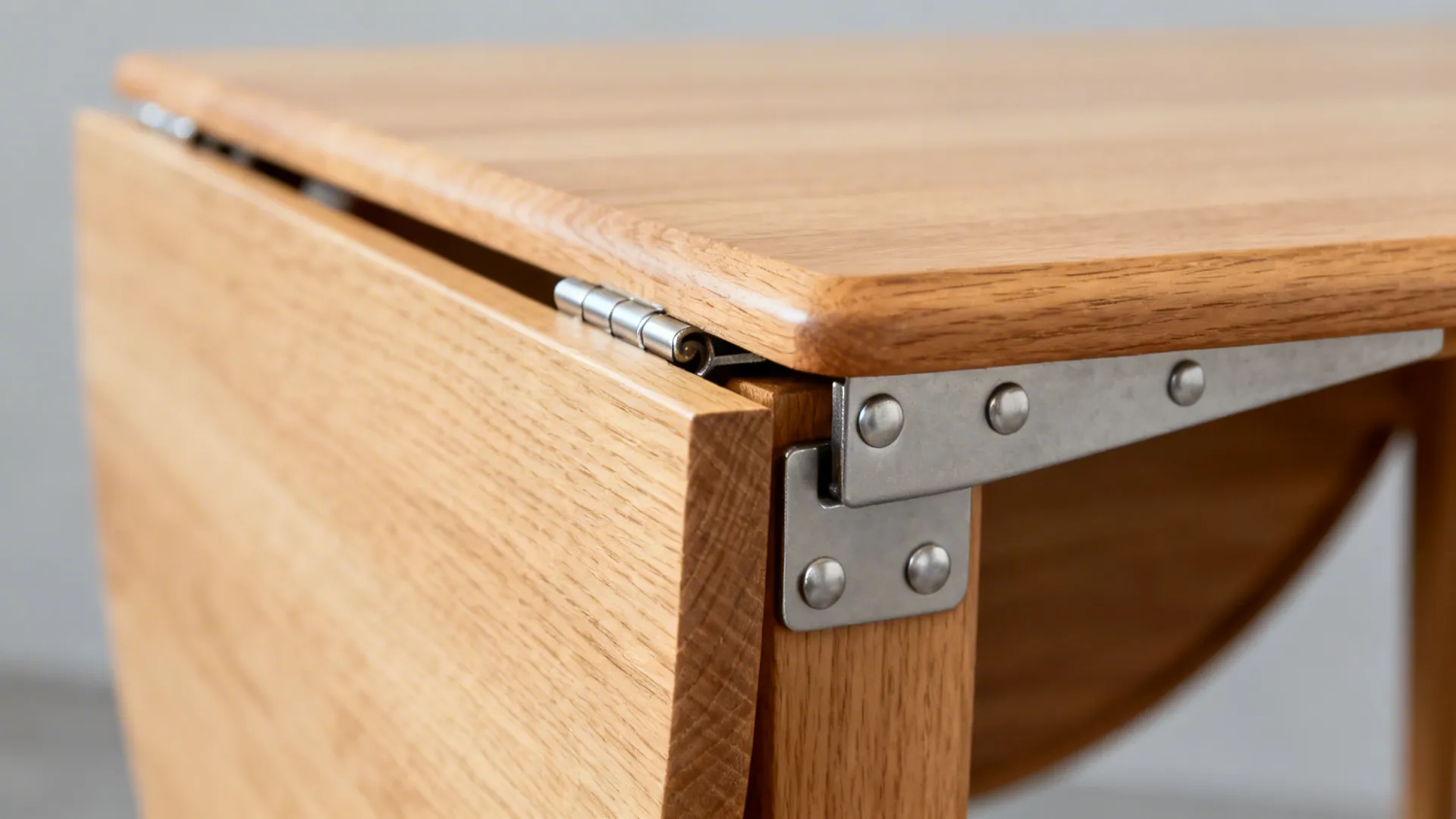 Close-up of a piano hinge and steel bracket on a maple drop-leaf table.