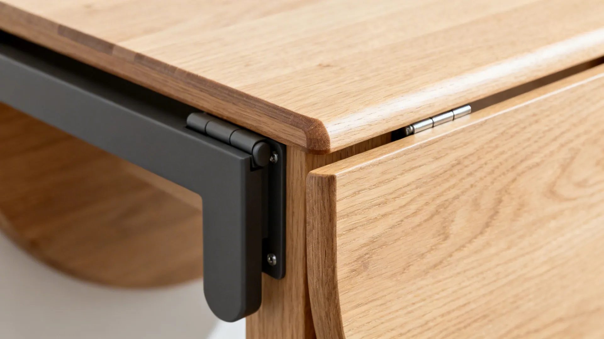 Close-up of a drop-leaf table’s hinge and soft-close hardware with ash wood veneer.