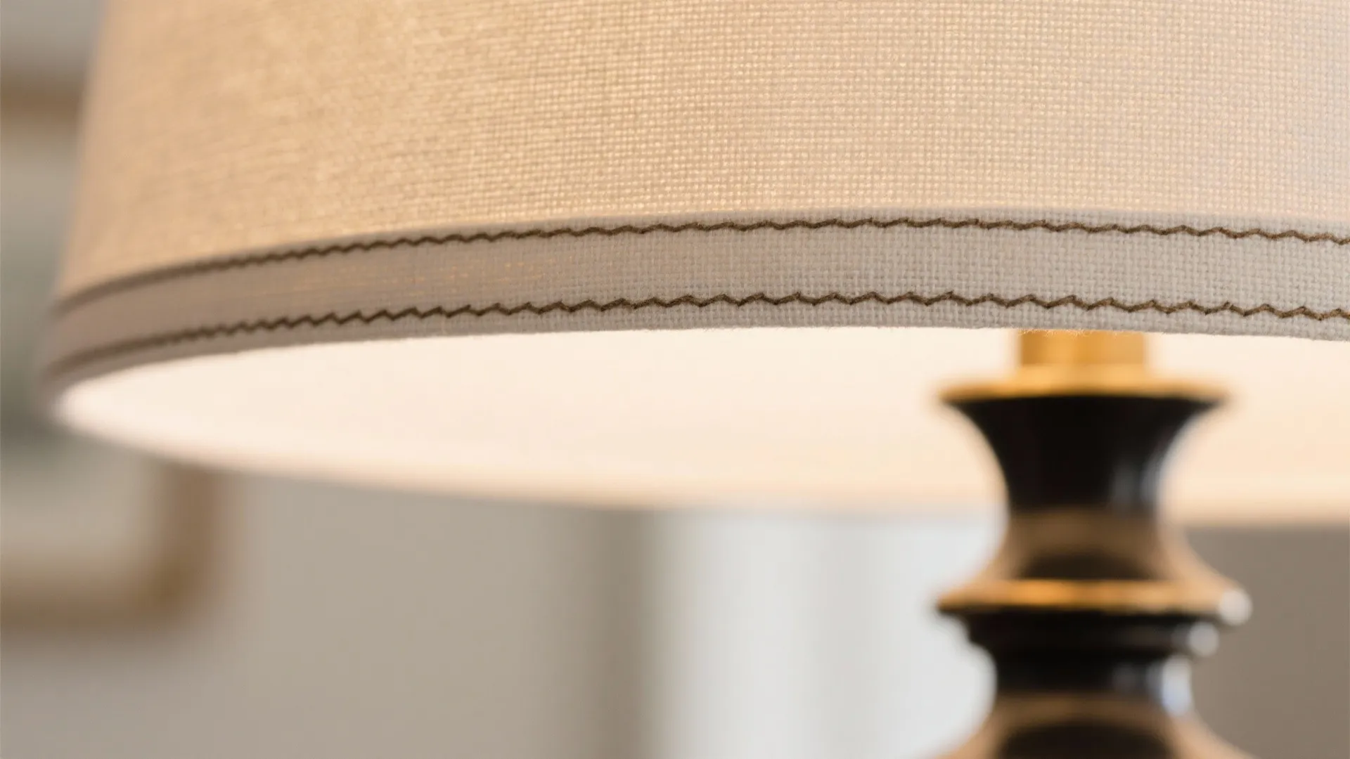 Close up view of a fabric table light shade with detailed stitching and a dark base