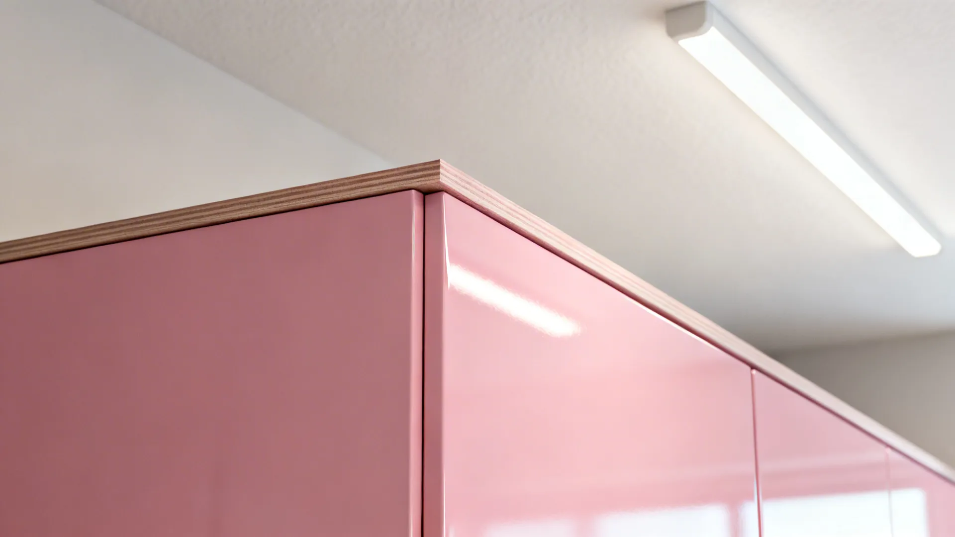 Macro details of pink cabinet finishes, edge-banding, and LED light reflection on neutral paint.