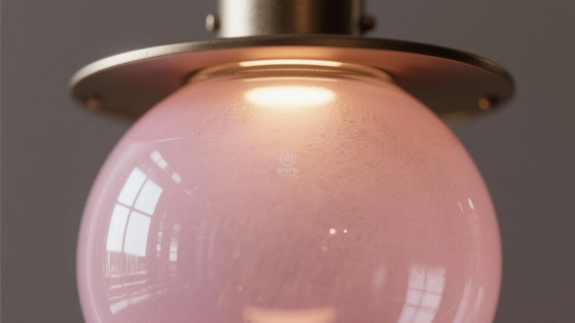 Close up of pink frosted glass light fixture with soft glowing light and metal base