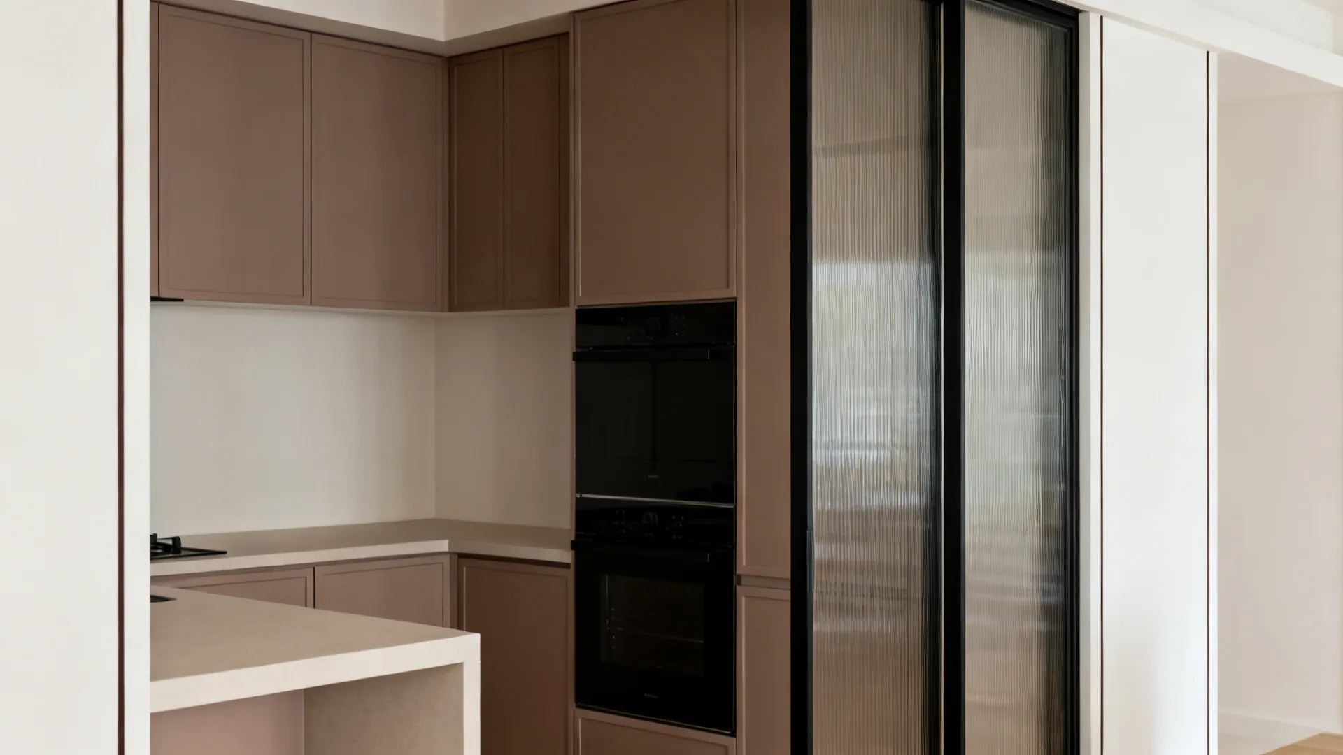Taupe cabinets with black appliances and a black-framed reeded glass feature in a small kitchen.