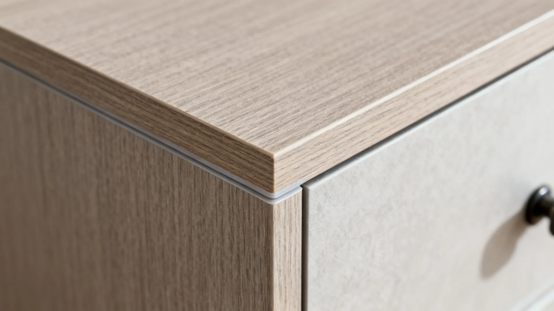 Close up view of a wood cabinet corner showing the edge finish and light grey