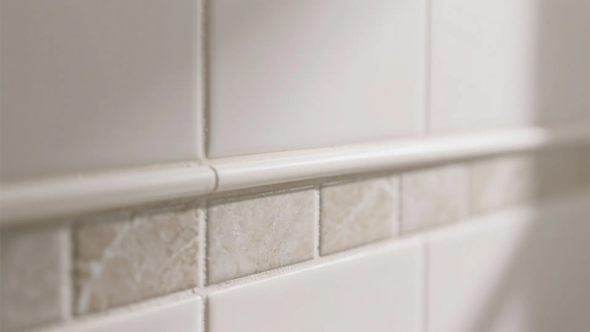 Macro of edge trim and silicone bead on peel-and-stick tiles with flat, prefilled grout lines for a seamless finish.