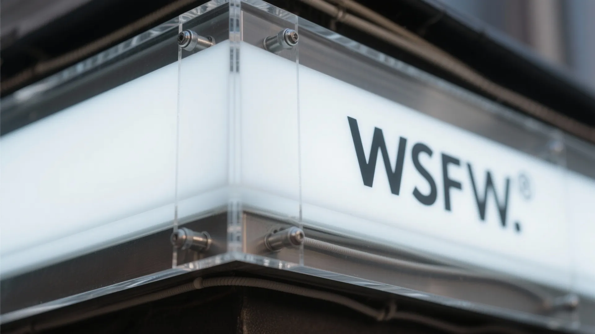 Close up of an outdoor wall light fixture with a logo printed on white glass