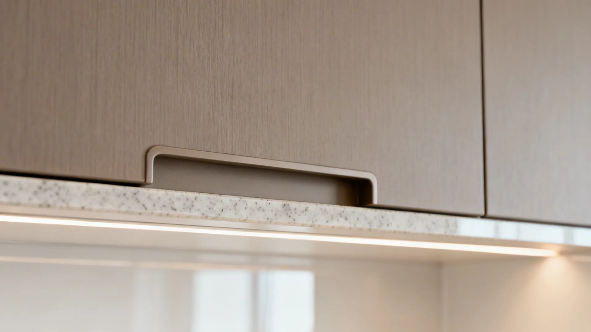 Macro of integrated edge pull on a matte slab cabinet door with subtle laminate texture.