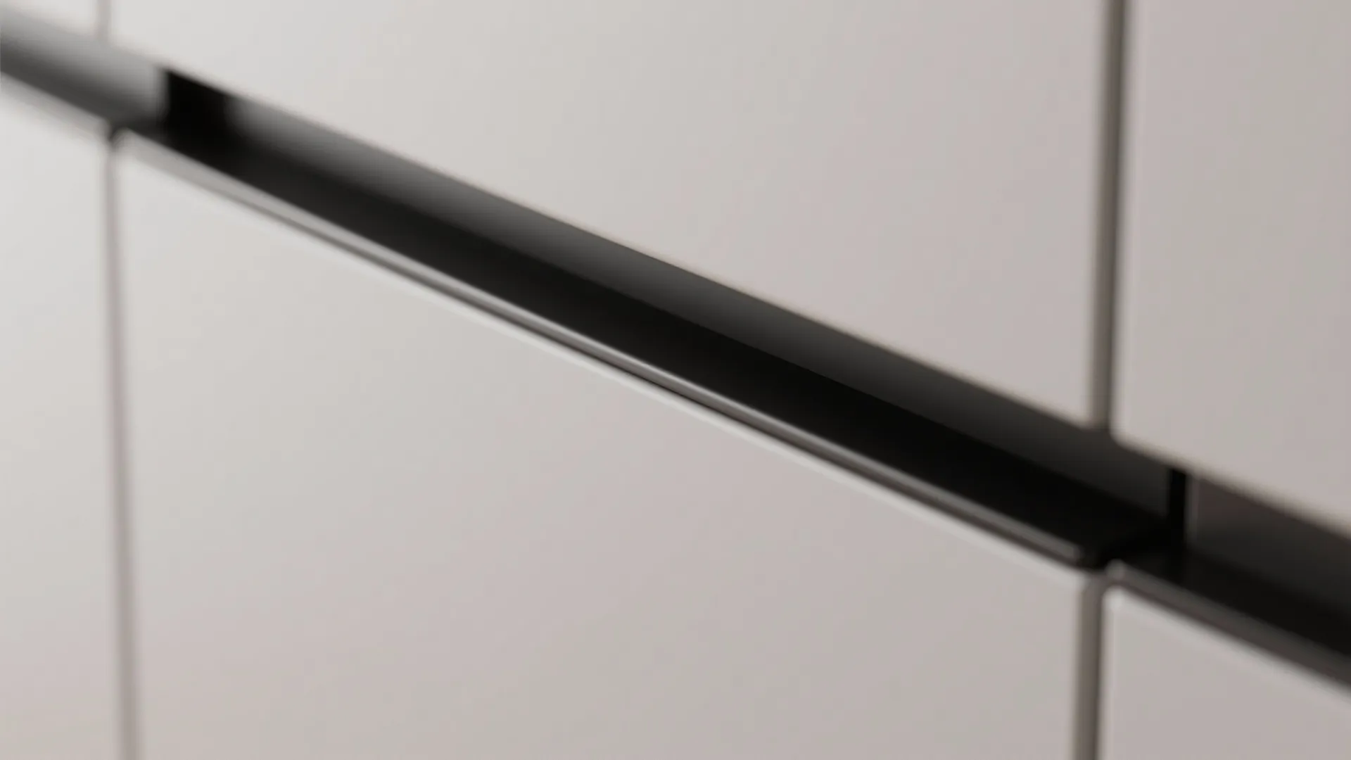 Modern black long handles installed on light grey cabinet doors for a minimalist kitchen storage