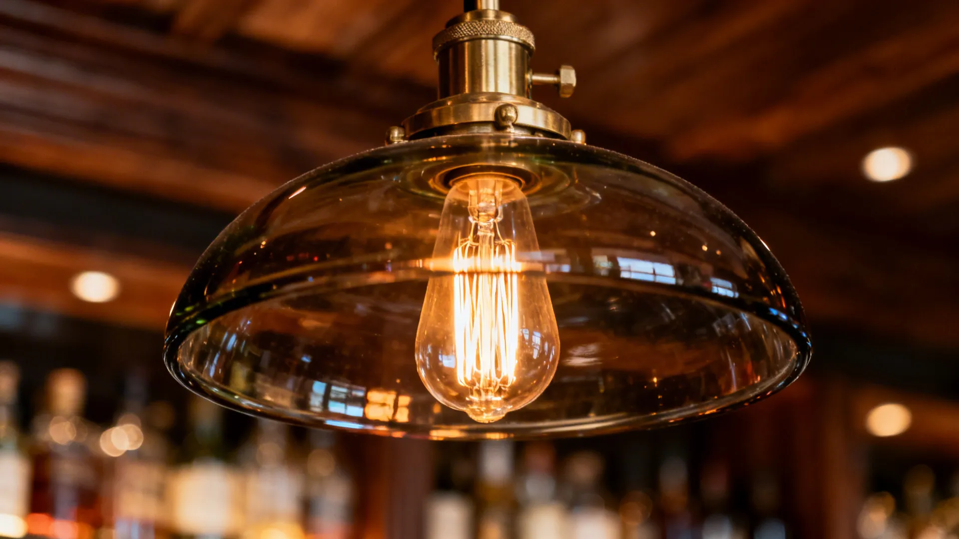 Close-up of an Edison-style filament LED glowing warmly inside a smoked glass chandelier shade.