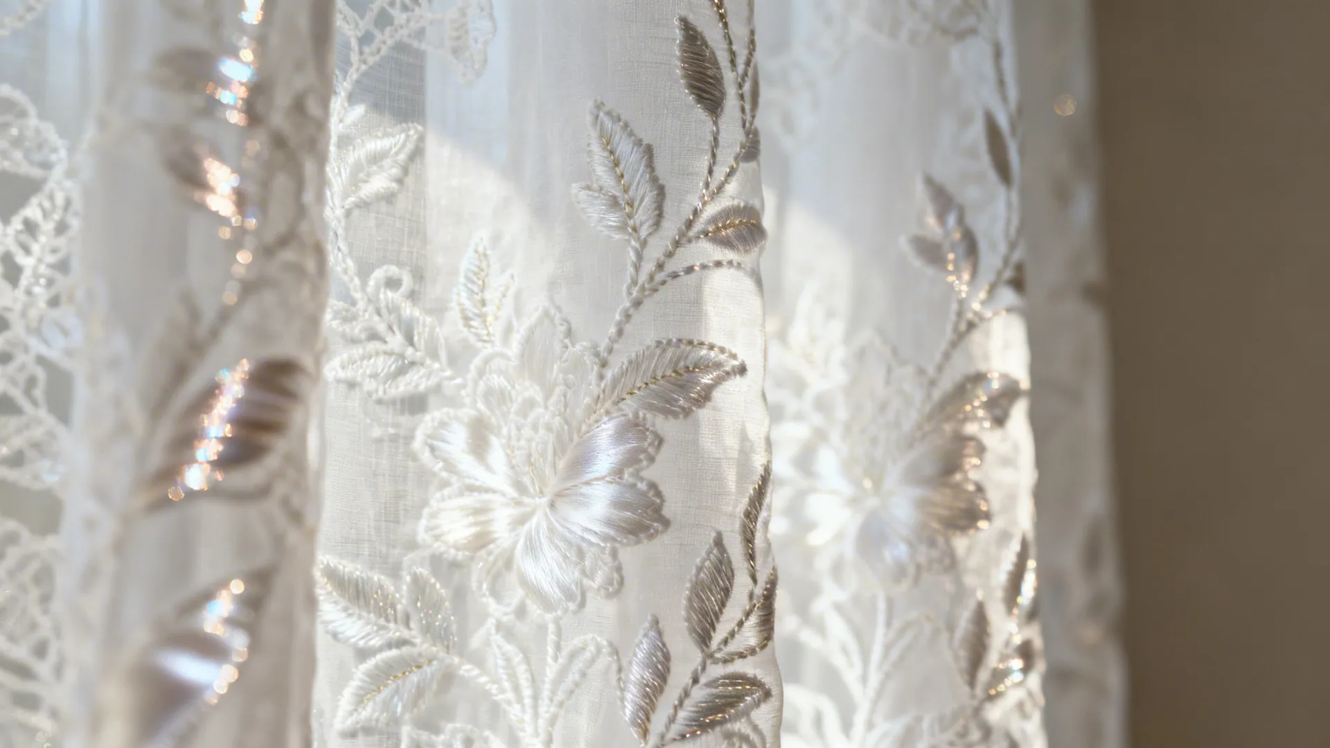 Close-up of white embroidered lace curtain with silk-thread accents and fine stitching.