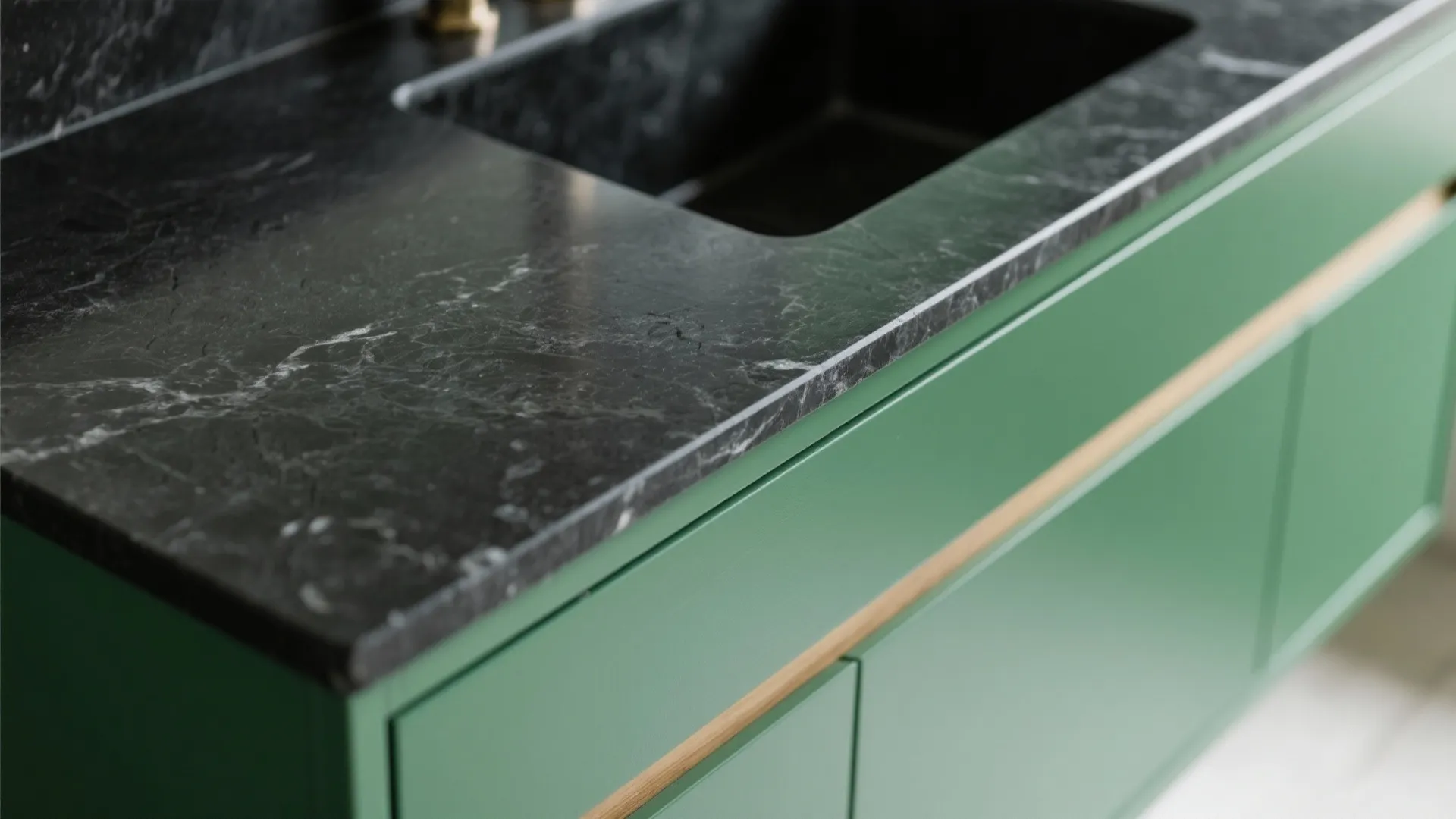 Close view of green bathroom cabinet with black marble counter top and a black sink