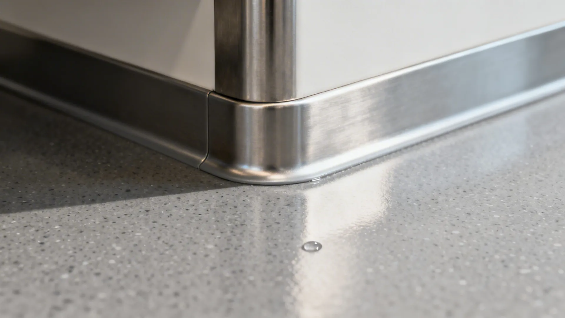 Macro of a seamless epoxy cove at floor-to-wall and stainless bench interface.