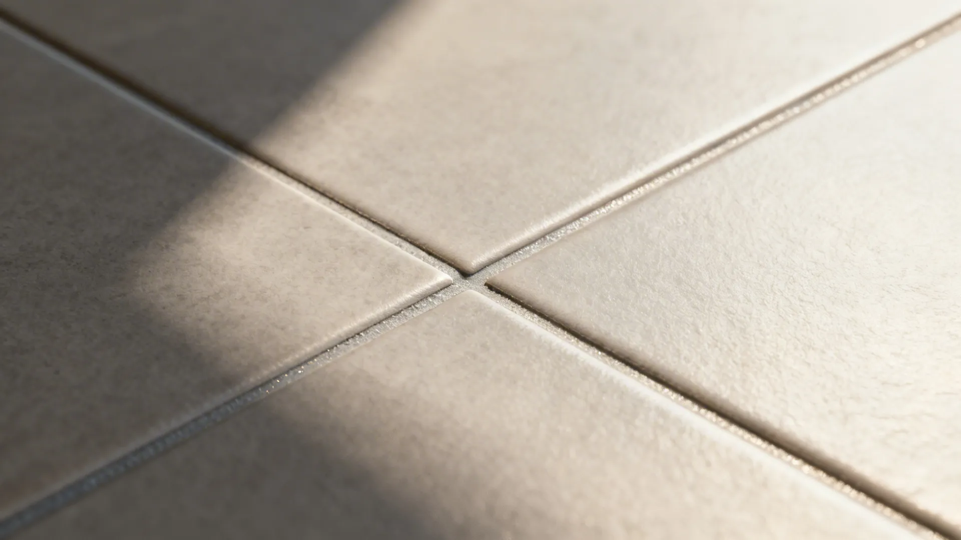Macro of 2–3 mm warm gray epoxy grout line between large porcelain tiles.