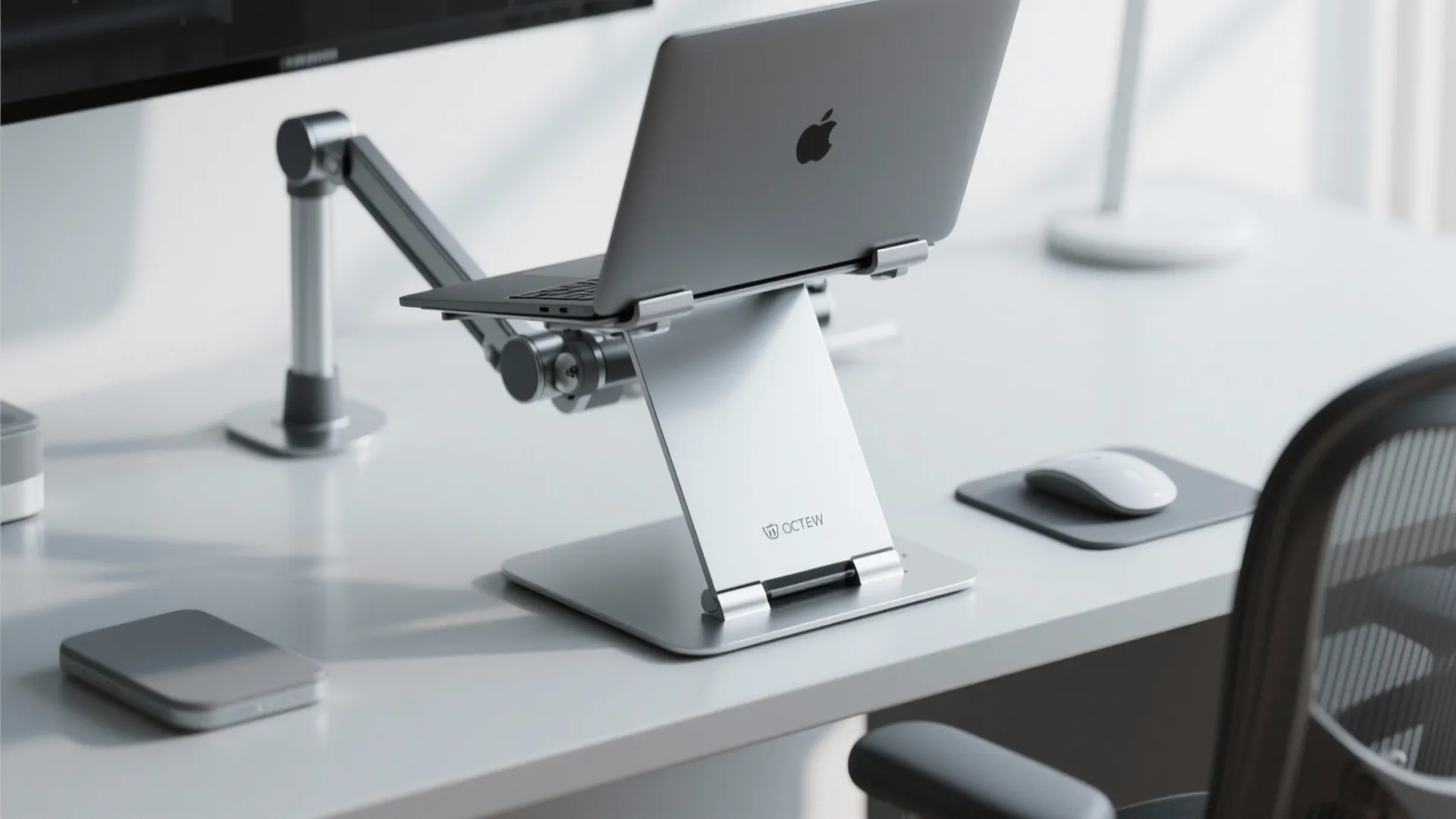 Modern office desk with silver laptop stand and laptop next to a white computer mouse