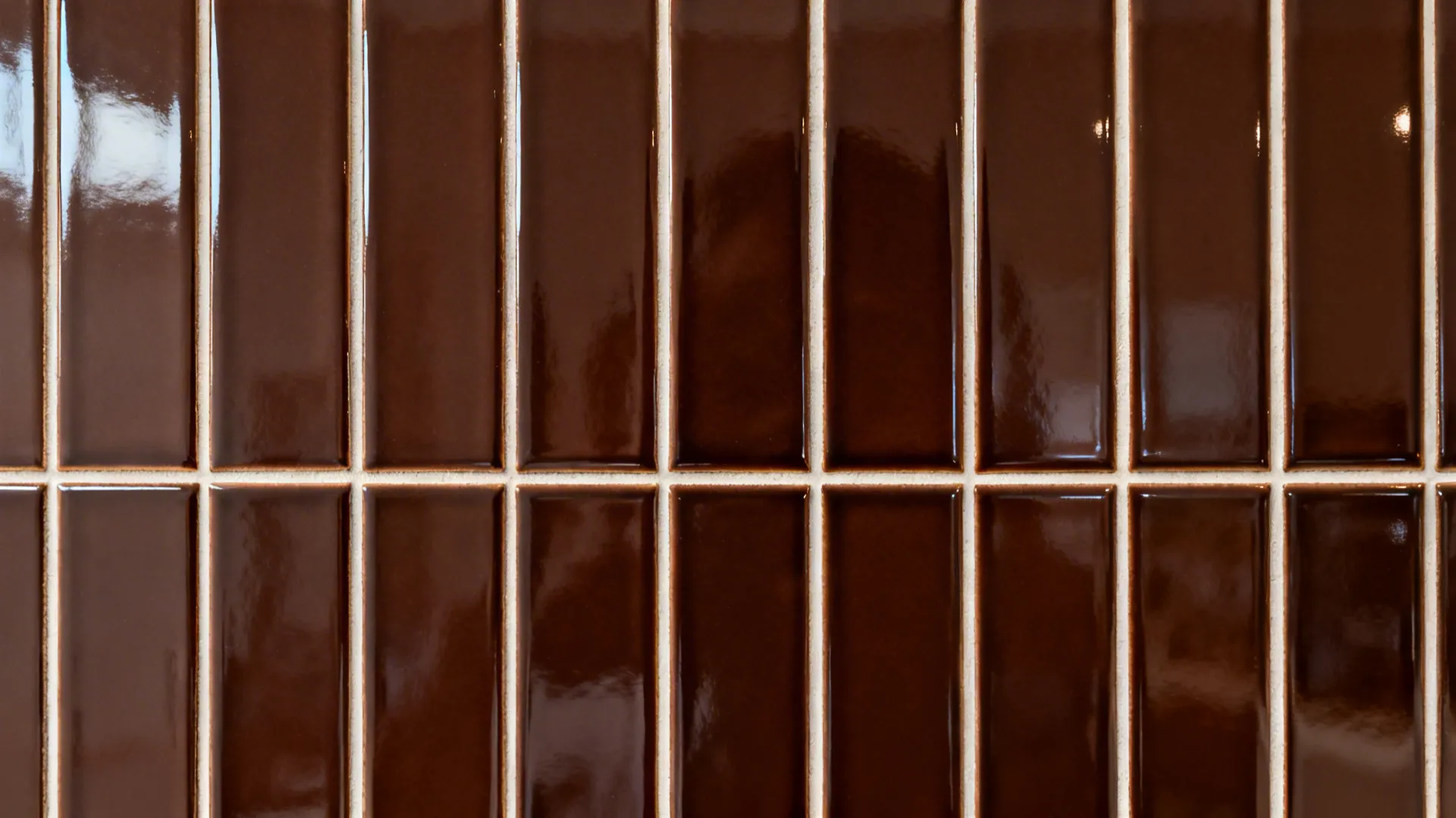 Macro of glossy espresso stacked tiles with precise grout lines and trim.