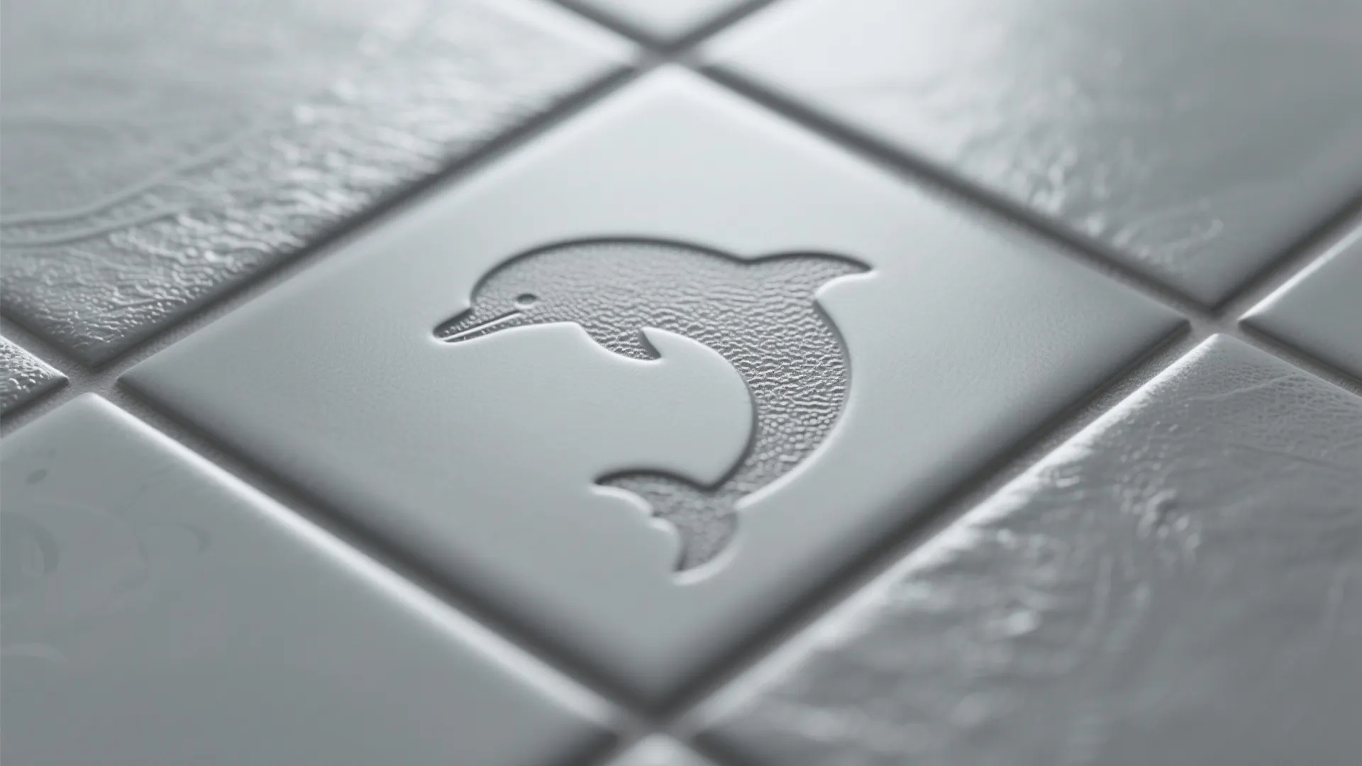 Close up of grey square floor tiles with an etched dolphin pattern in the center