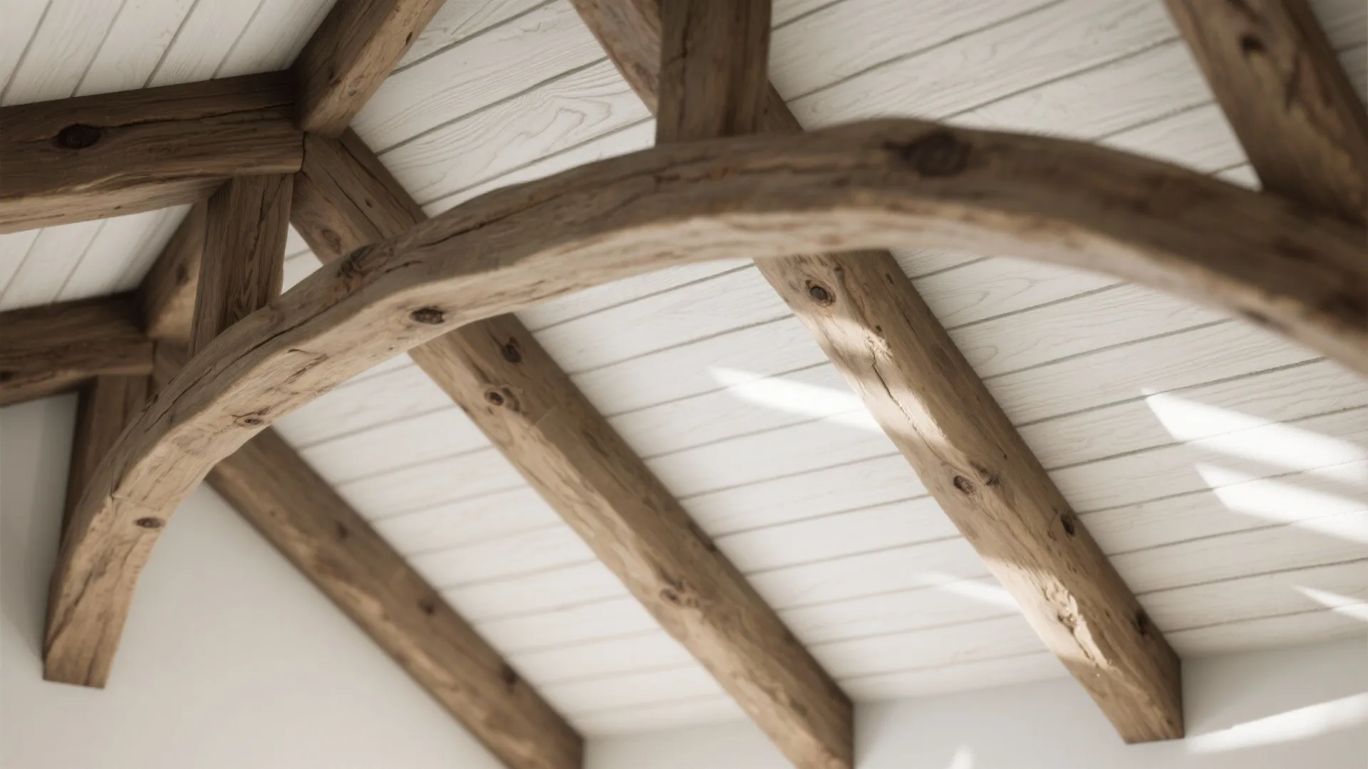 Macro detail of exposed wooden beams and tongue-and-groove ceiling in a vaulted kitchen.