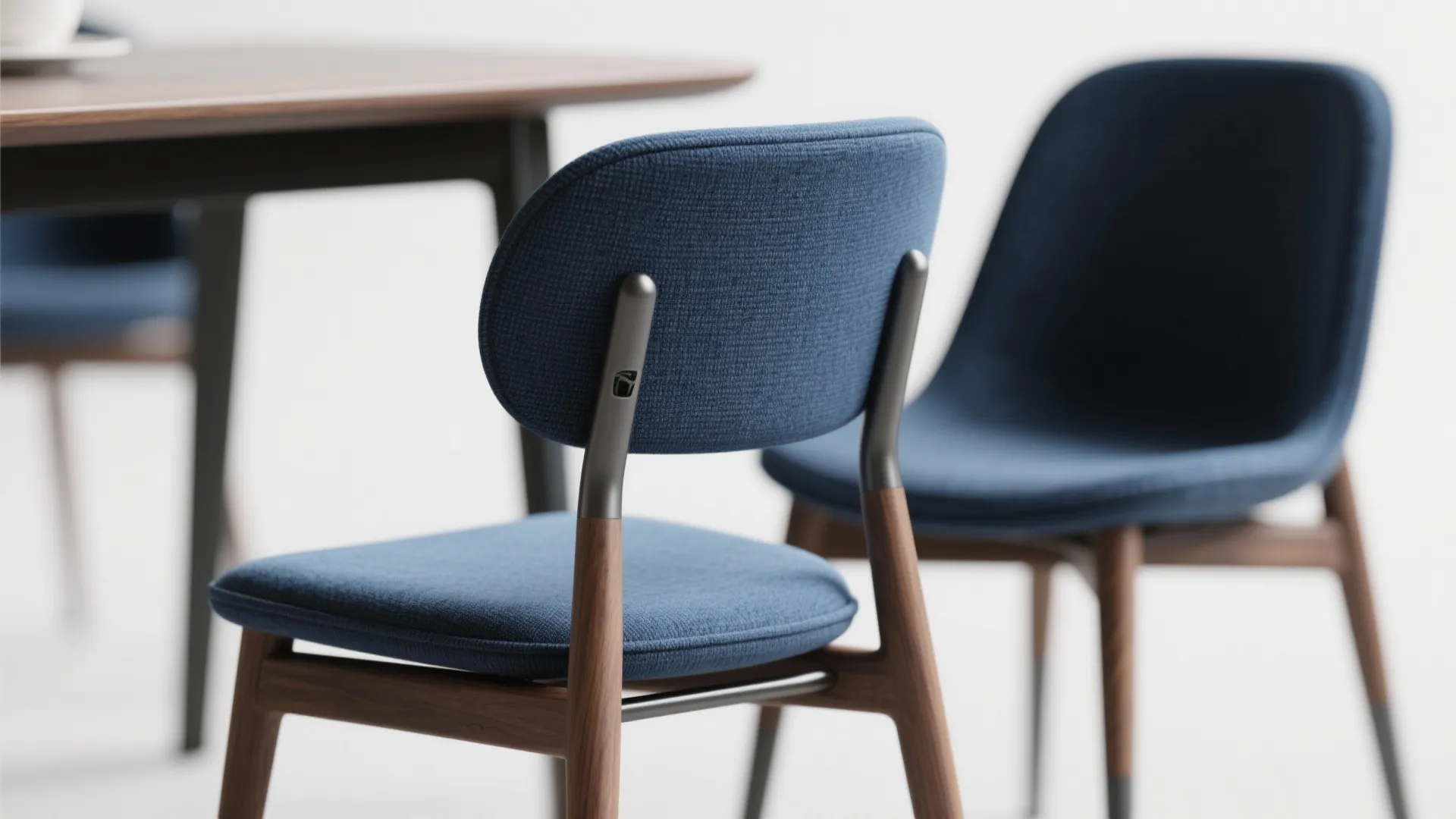 Close up showing blue fabric chairs with wooden legs next to a dark wood dining table